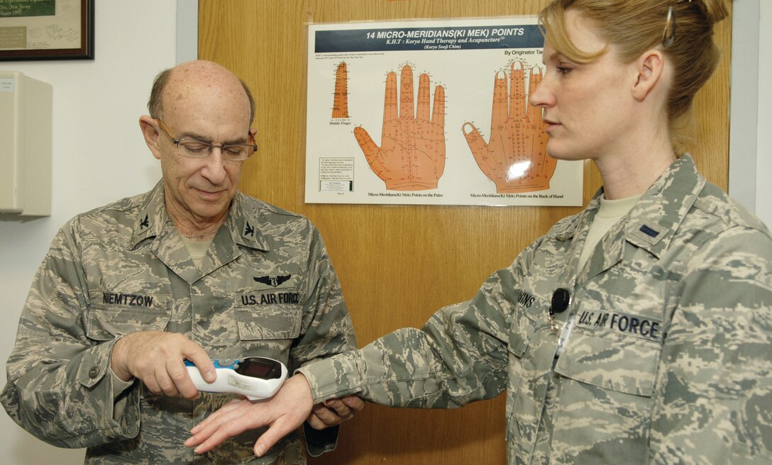 Colonel Richard Niemtzow, Air Force Surgeon General Consult for Complementary and Alternative Medicine, uses an interxsport device, which emits electrical wave forms to treat inflamed muscle tissue, on 1st Lt. Jami Cavins, National Guard Bureau logistics readiness officer, at Malcolm Grow Medical Center March 11. (U.S. Air Force photo/ Senior Airman Renae Kleckner)