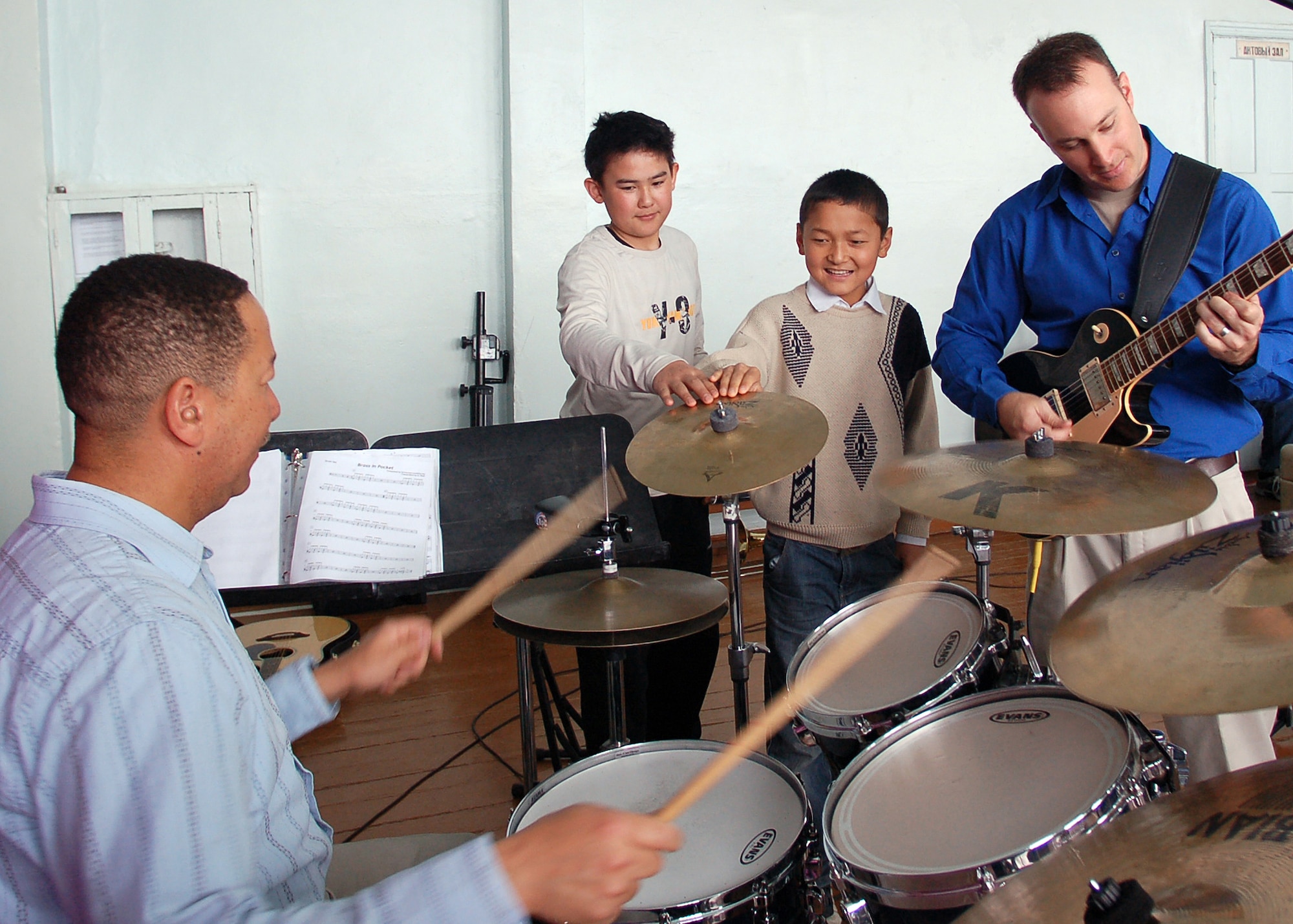 Two students get a literal feel for music as drummer Master Sgt. Clarence Carpenter of Sebring, Fla., rocks on and Staff Sgt. Gene Dooley of Graham, Texas, provides rhythm guitar during a concert by the AFCENT Band "Sirocco" at the Bishkek Boarding School for the Deaf, Kyrgyz Republic.  The 10-member band is deployed from Sembach Air Base, Germany, and provides educational activities and a positive
vision for community school outreach events throughout a 27-nation area of
responsibility. (U.S. Air Force photo by Tech. Sgt. Elizabeth Weinberg)
