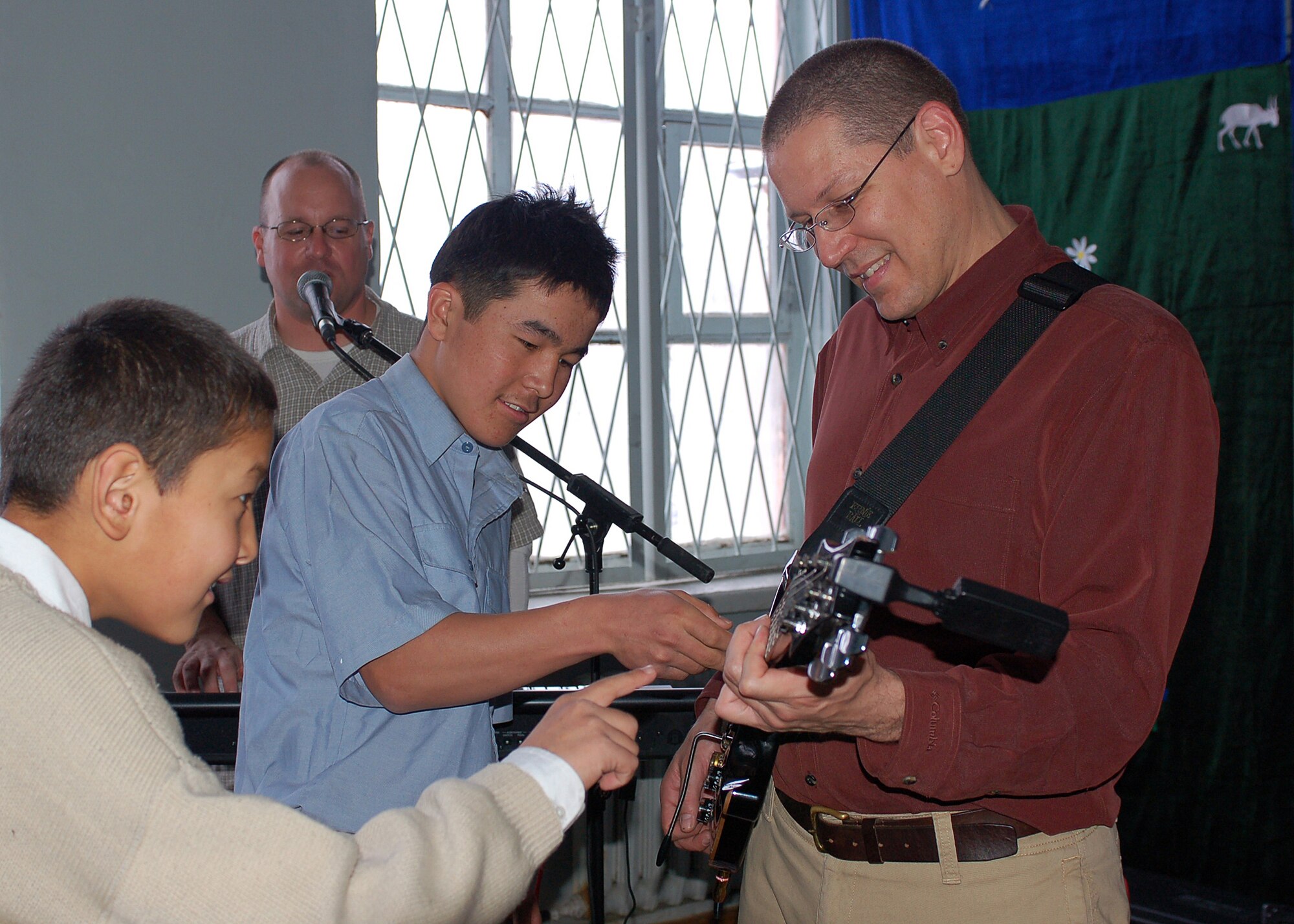 Two students provide some extra pluck for Staff Sgt. Paul Wells at the
Bishkek Boarding school for the Deaf in the Kyrgyz Republic as Master Sgt.
John Link of Enfield, Conn., provides keyboard backup.  Sergeant Wells, a
native of Tampa Bay, Fla., plays guitar with the AFCENT Band "Sirocco," part
of the United States Air Forces in Europe Band and is deployed from Sembach
Air Base, Germany. The 10-member group's mission -- in addition to troop morale --
is to help offer a positive vision and nurture common interests and values
in the U.S. Central Command area of responsibility.  (U.S. Air Force photo by Tech. Sgt. Elizabeth Weinberg)