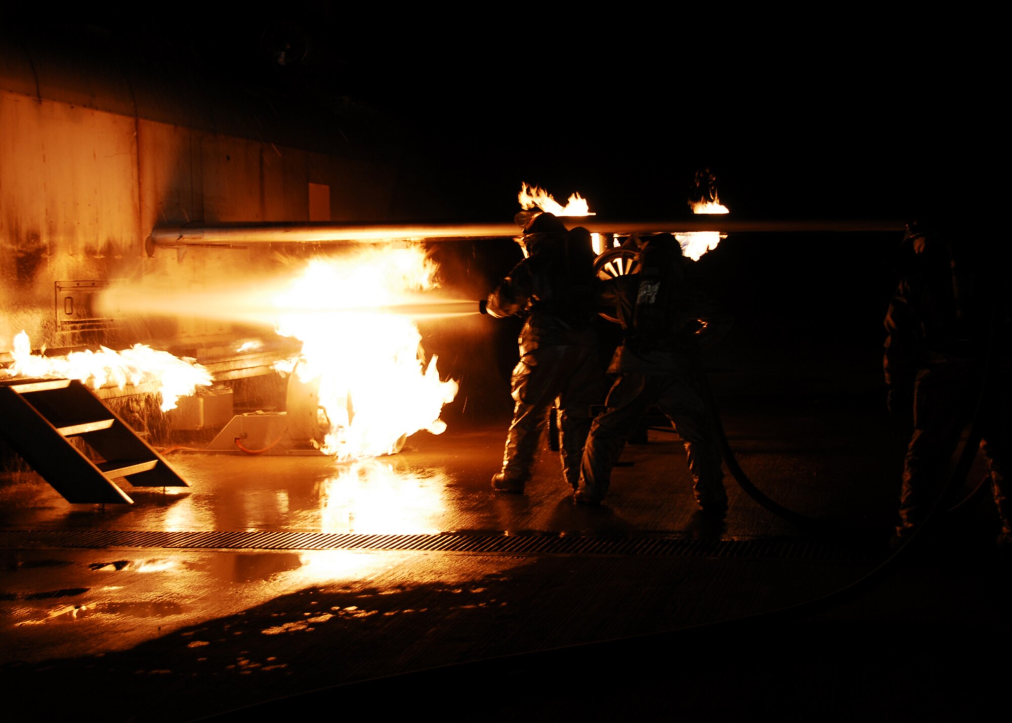 SOUTHWEST ASIA -- Firefighters from the 386th Expeditionary Civil Engineer Squadron utilize teamwork and nozzle techniques to put out a simulated aircraft fire during live fire burn training at an Army base in Southwest Asia, March 18. The training gives the firefighters a realistic experience, allowing them to understand the importance of training, teamwork and safety. (U.S. Air Force photo/ Senior Airman Courtney Richardson)
