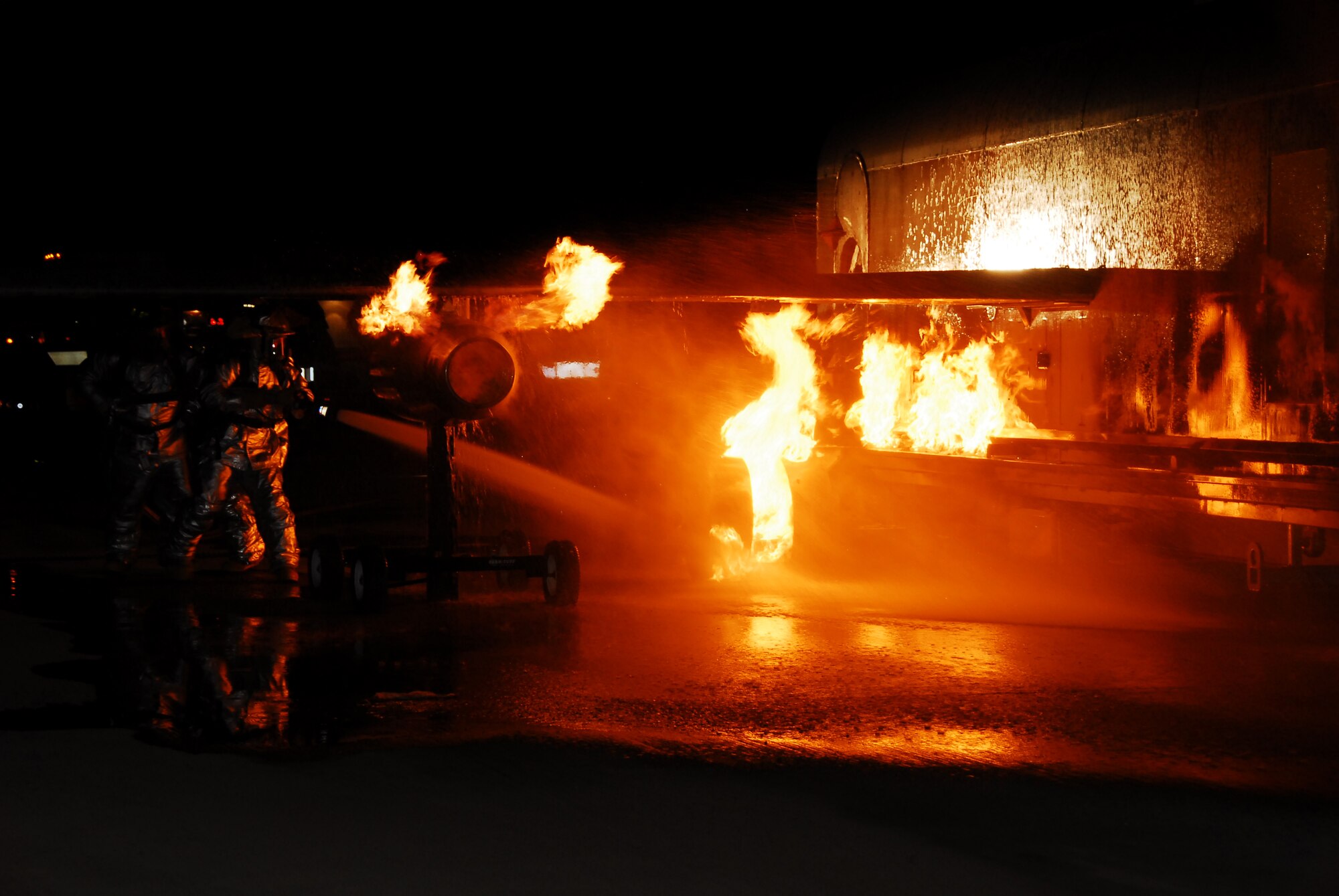SOUTHWEST ASIA -- Firefighters from the 386th Expeditionary Civil Engineer Squadron work together to put out a simulated aircraft fire during live fire burn training at an Army base in Southwest Asia, March 18. The training required the firefighters to put out fires in different areas of the aircraft as well as rescuing two simulated victims that were located inside the aircraft. (U.S. Air Force photo/ Senior Airman Courtney Richardson)