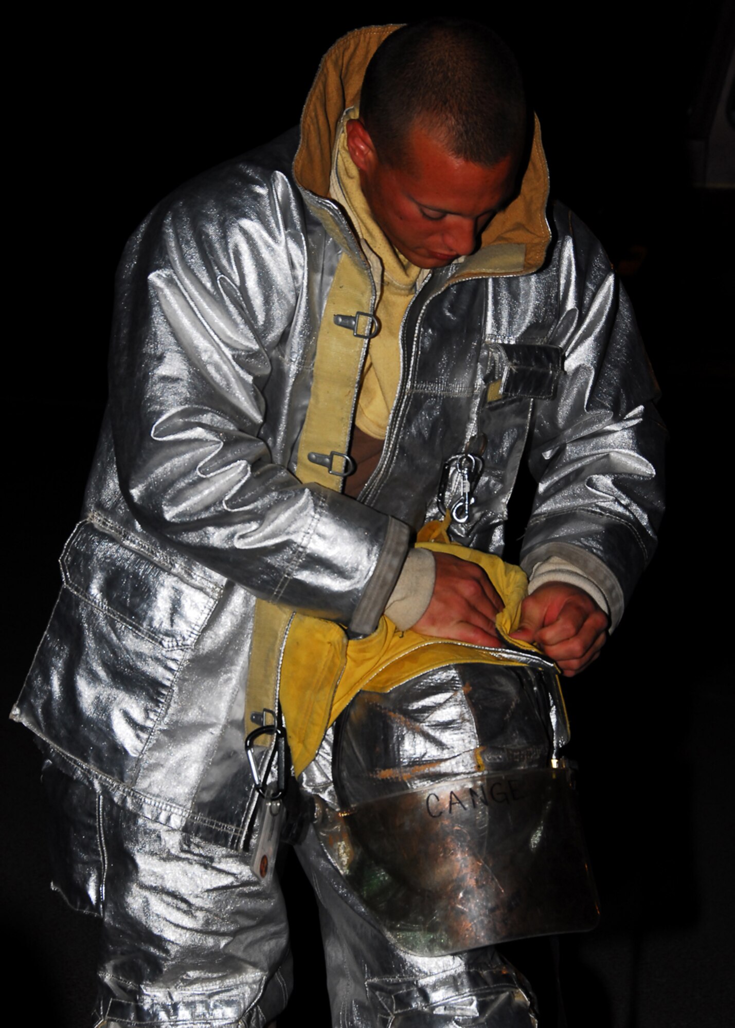 SOUTHWEST ASIA -- Airman 1st Class Paul Cange, 386th Expeditionary Civil Engineer Squadron firefighter, adjusts his helmet before live fire burn training at an Army base in Southwest Asia, March 18. Air Force firefighters must complete one daytime and nighttime live fire burn annually including interior and exterior fires. Airman Cange is currently deployed from Francis S. Gabreski Air National Guard Base, N.Y. and is originally from Rocky Point, N.Y. (U.S. Air Force photo/ Senior Airman Courtney Richardson)