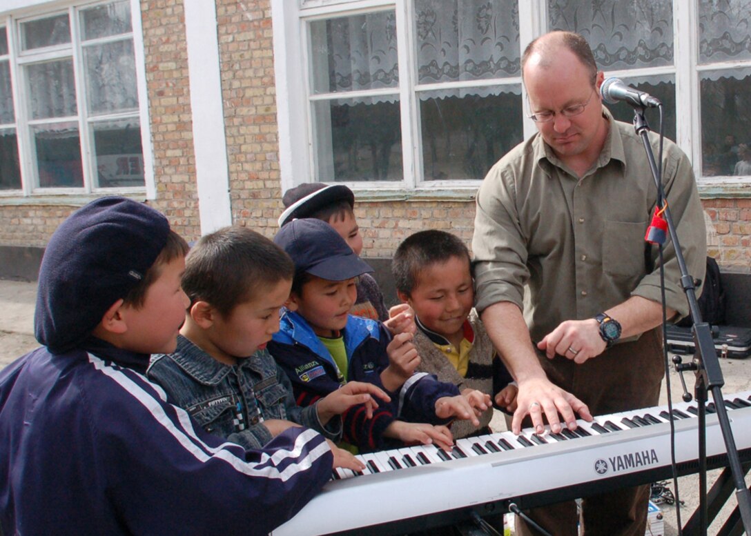 Master Sgt. John Link shares the joy of making music with children at the Nizhanchuisk Orphanage March 15 near Manas Air Base, Kyrgyzstan. Sergeant Link is the keyboardist and non-commissioned officer in charge of Sirocco, the U.S. Air Forces Central Expeditionary Band touring the AFCENT area of operations. During their 12-day Manas visit, the band has played at a local orphanage, four special needs schools and a music college. The band members are deployed from the U.S. Air Forces in Europe Band at Sembach AB, Germany. Sergeant Link is originally from Entfield, Conn. (U.S. Air Force photo/Tech. Elizabeth Weinberg)