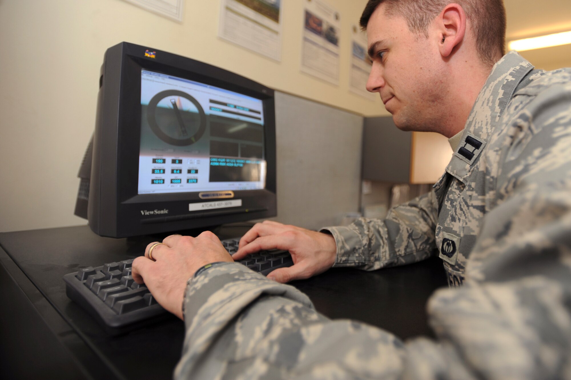 Capt. Jeffrey Cunningham, 379th Expeditionary Operation Support Squadron Weather Flight commander, checks readings from an FM-Q19 Airfield Sensor here March 19. Captain Cunningham is scheduled to teach a meteorlogy course next semester and while still completing his normal duties. The FM-Q19 is an in-place instrument for reading wind direction, temperature and humidity on the airfield.  (U.S. Air Force Photo by Staff Sgt. Joshua Garcia)