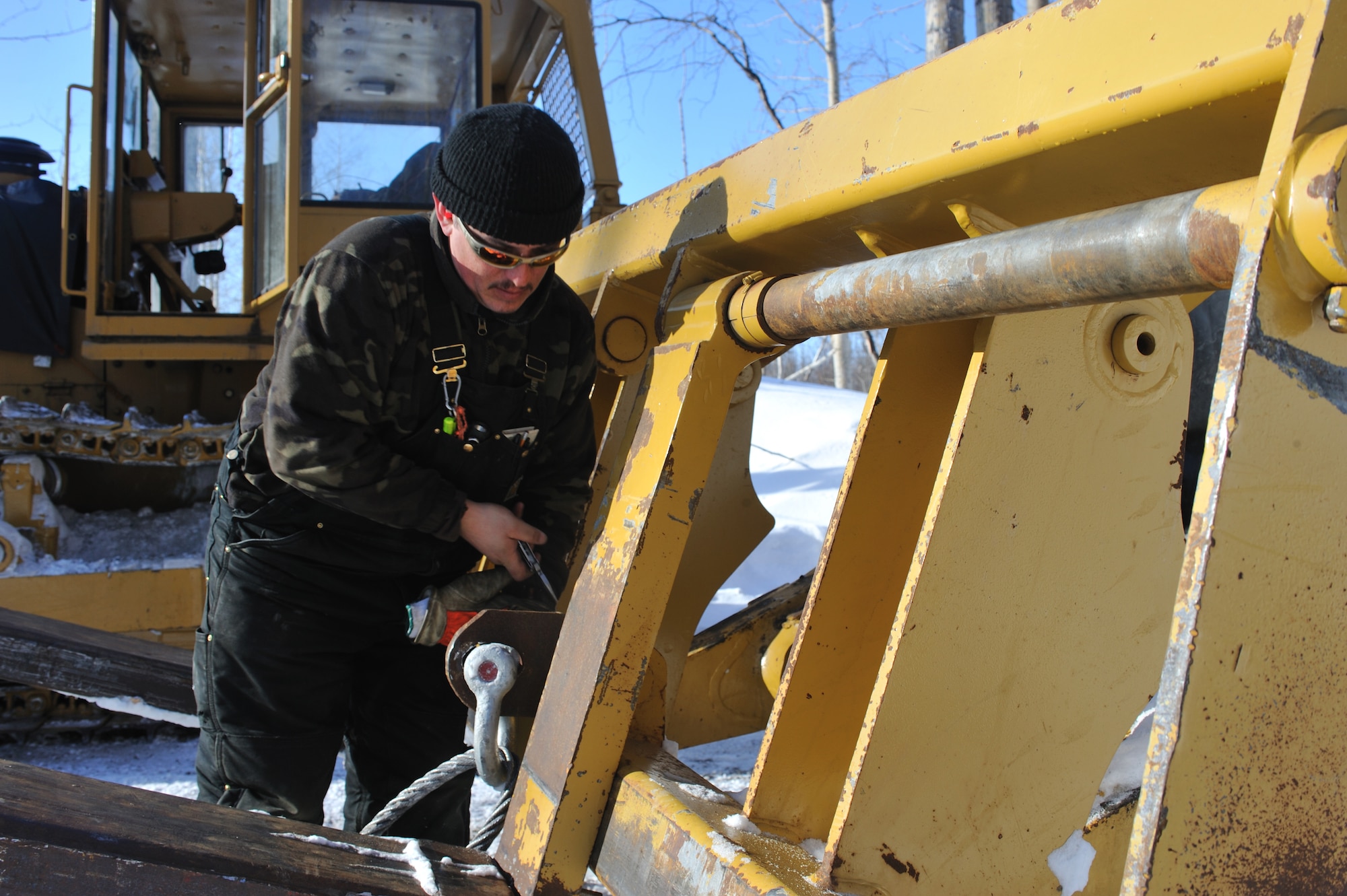 GALENA, Alaska-- Derek Gronlund, a Marsh Creek LLC employee, attaches a shackle to a forklift to pull a cat train full of supplies toward Kalakaket Creek, March 17. Marsh Creek LLC, a contractor for the 611th Civil Engineer Squadron, is building an ice bridge to move supplies for demolition of the former Kalakaket Creek Radio Relay Station that is located 310 miles northwest of Anchorage. The station was built in 1957 and was used to transfer defense communications between White Alice Communication Systems up for demolition because of satellite technology in mid 1970s. (U.S. Air Force photo by Senior Airman Jonathan Steffen)