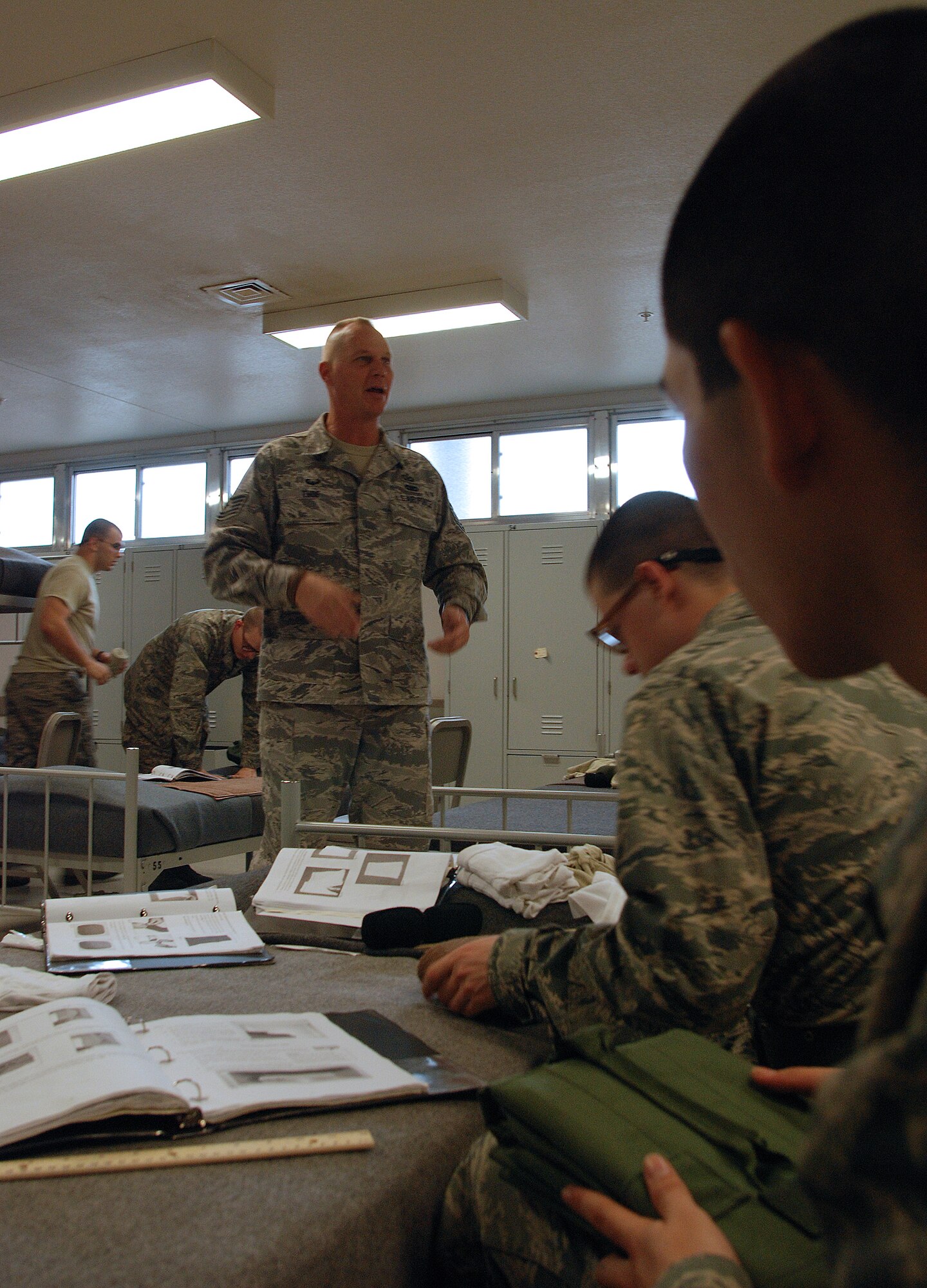 Technical Sgt. Terrance Thoe, a Reserve military training instructor from the 433rd Airlift Wing, explains, to trainees from the 326th Training Squadron, the importance of following directions and attending to detail as they fold and roll the contents of their first-issue clothing drawers. Reservists work in concert with active-duty Airmen to accomplish the missions. (U.S. Air Force photo/Airman Brian McGloin)