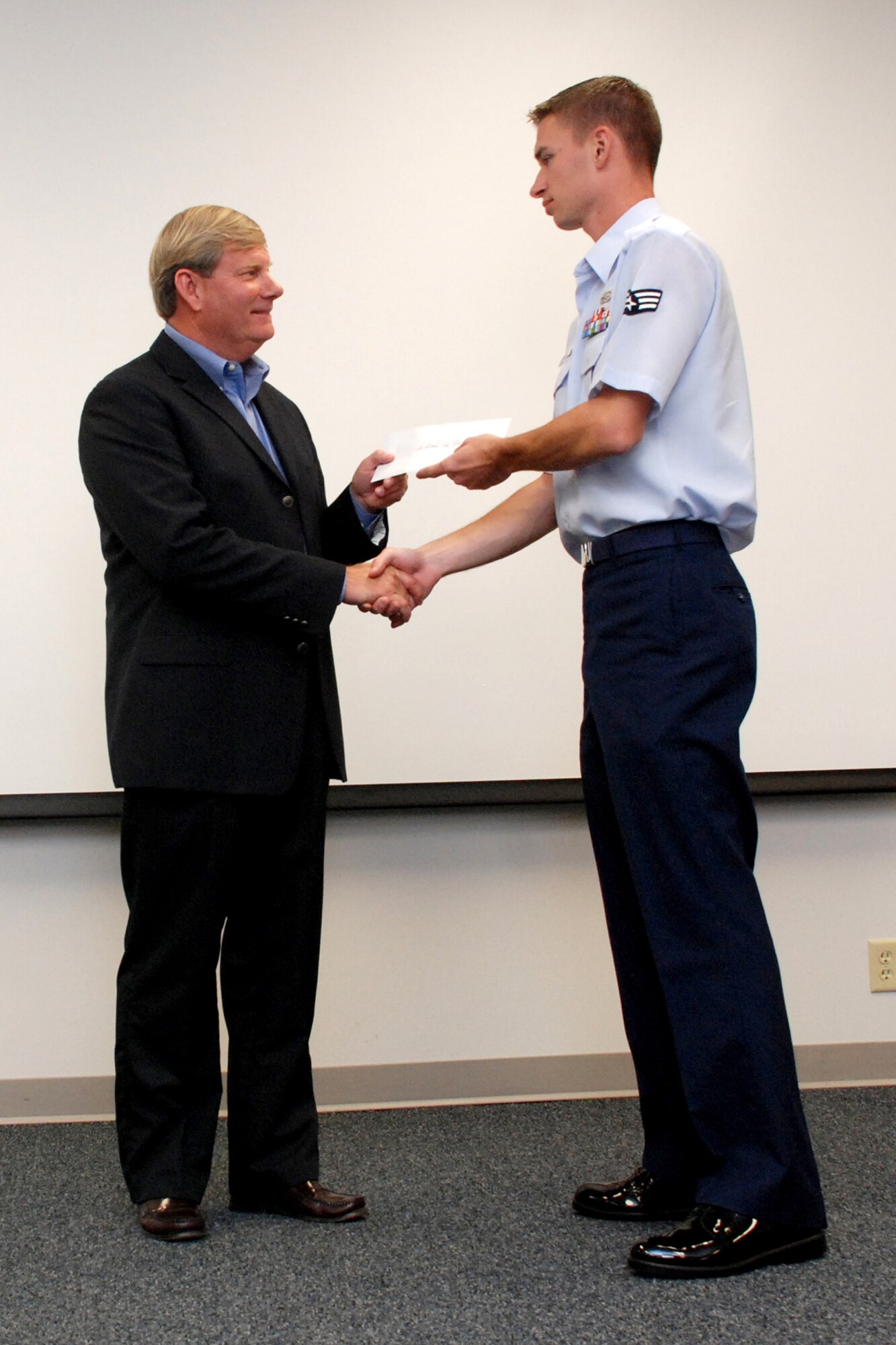 EGLIN AIR FORCE BASE, Fla. -- Ken Hair, Children in Crisis, Inc. executive director and a retired chief master sergeant, is presented a $200 check by Senior Airman Alex Kelley, 96th Mission Support Squadron and Airman Leadership School class leader, at the Enlisted Professional Development Center here March 23. The ALS class donated $200 to the local non-profit organization who provides homes and establishes hope to abused, neglected and abandoned children in the local community. The goal of ALS is to develop Airmen into effective front-line supervisors in the noncommissioned officer corps. (U.S. Air Force photo by Staff Sgt. Mike Meares)