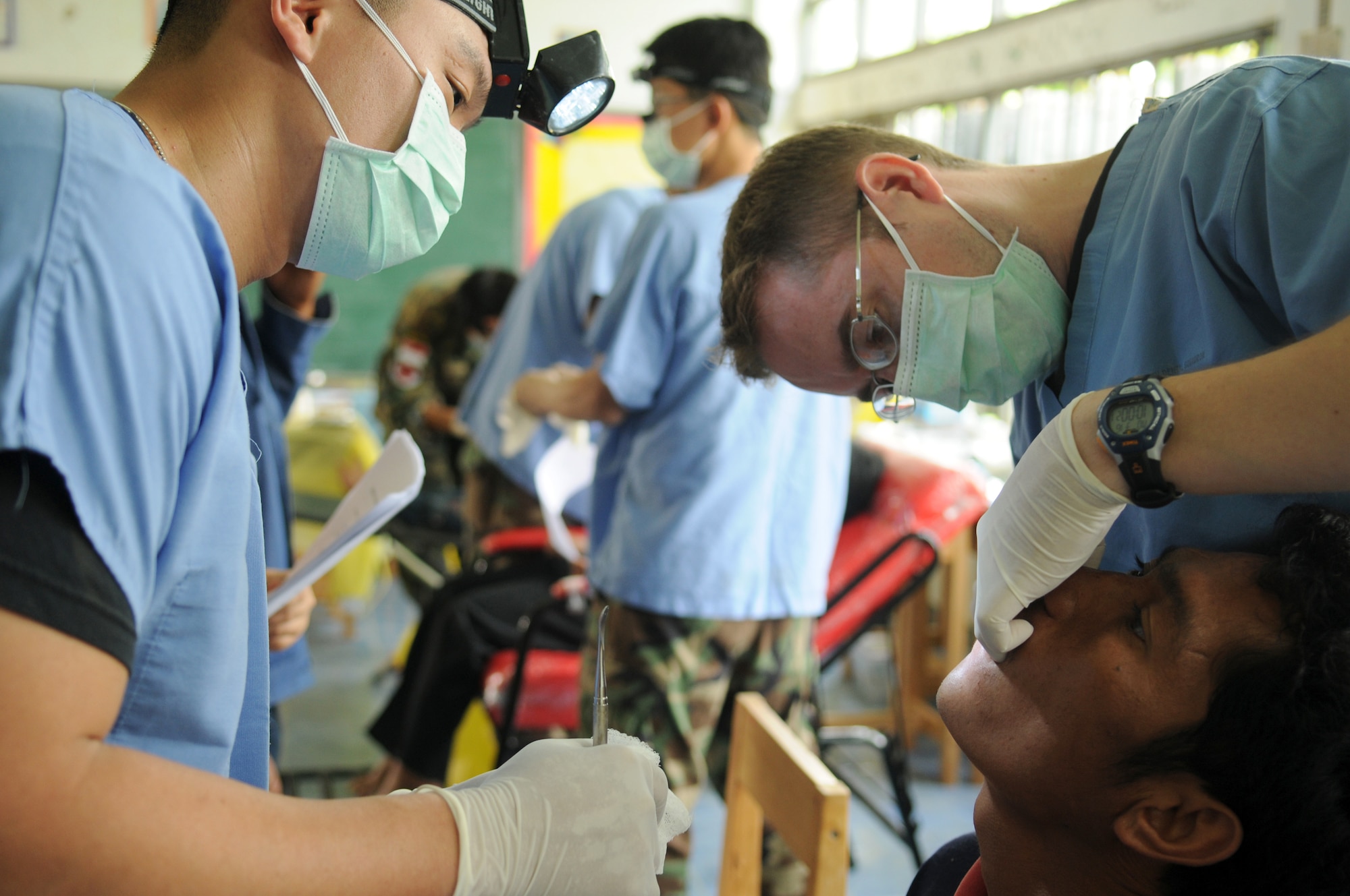 Staff Sgt. Scotty Scott (left) assists Capt. Dana Jensen (right) with a tooth extraction during a joint and multinational humanitarian mission to provide much needed dental care to Thailand's underprivileged during Cope Tiger 2009 on March 16. Cope Tiger is an annual exercise conducted in Thailand to improve combat readiness and combined and joint interoperability of U.S., Thai and Singaporean forces while enhancing regional security and providing humanitarian support. Captain Jensen is a dentist from the 18th Dental Squadron at Kadena Air Base, Japan. Sergeant Scott is a dental technician from the 374th Dental Squadron at Yokota AB. (U.S. Air Force photo/Staff Sgt. Angelique Perez) 