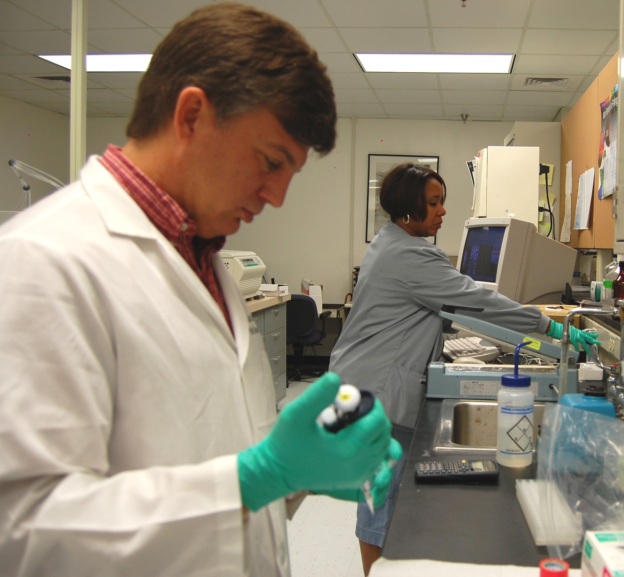 Michael Hart uses a pipette to place DNA samples into a microfuge tube as Bridgette Parks prepares reagents for DNA testing.  Both are molecular genetics technologists in the medical genetics laboratory.  (U.S. Air Force photo by Steve Pivnick)