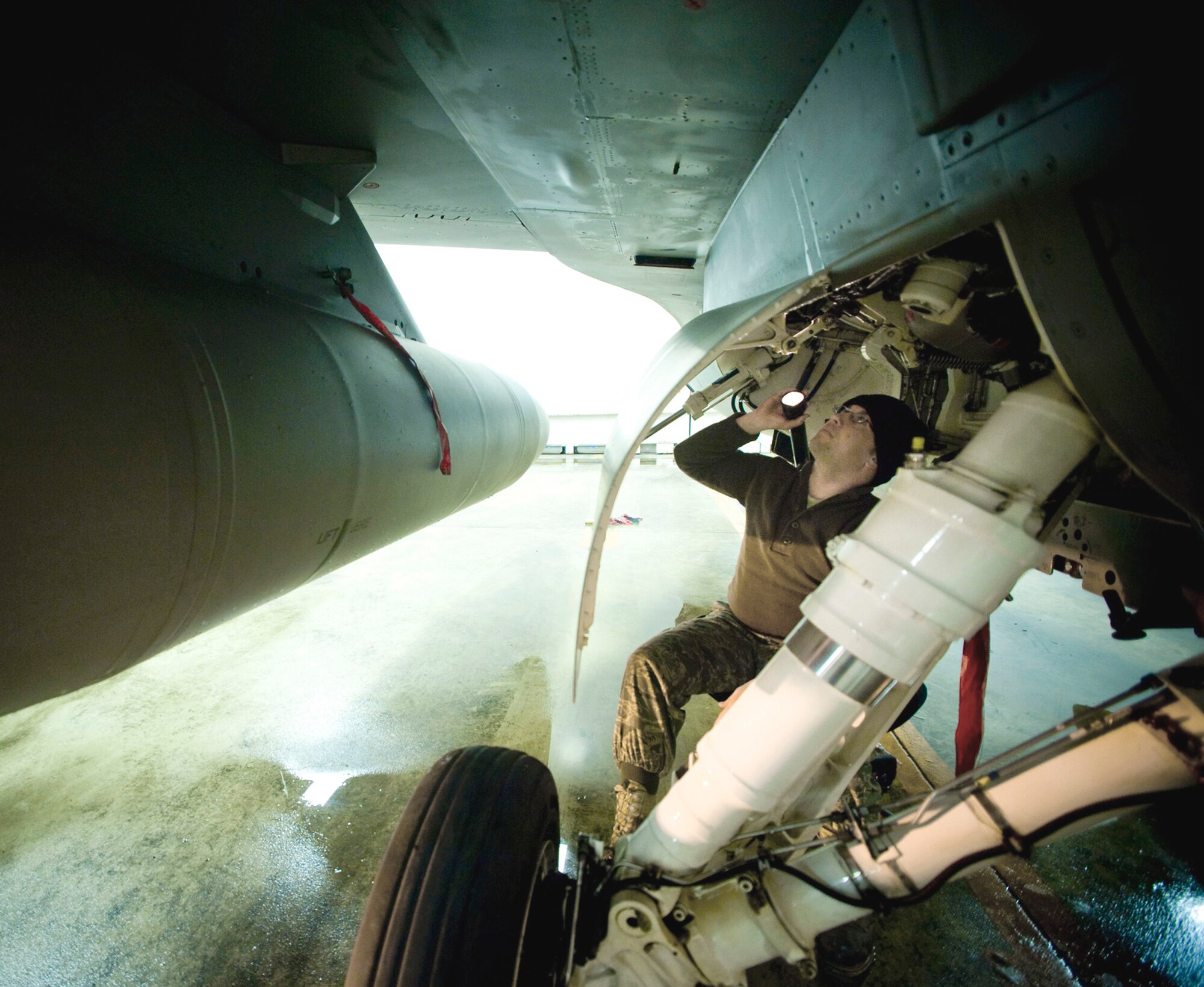 Staff Sgt. Brad Millhouse performs a quality assurance inspection on the landing gear of an F-16 Fighting Falcon March 6 at Misawa Air Base, Japan. Sergeant Millhouse, an Air National Guardsman F-16 crew chief deployed from the 122nd Fighter Wing from Fort Wayne, Ind., had to make sure the landing gear was re-lubricated properly after washing off sand from the jet's recent deployment to Iraq. (U.S. Air Force photo/Staff Sgt. Samuel Morse) 
