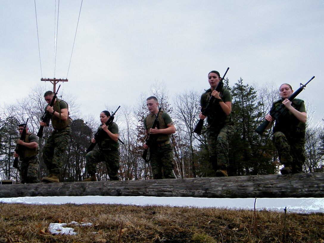 Westover Marines are put through the paces March 7 during training. Doing step-ups on a log by the Westover Club are, from left, Staff Sgt. Timothy Travers, Lance Cpl. William Costa (the winner), Private First Class Aurlina Perez, Lance Cpl. JonathanWright, Cpl. Yesseria Colon, and Lance Cpl. ChastityVangosen. The Marines did a two-minute drill after running 1.5 miles in boots, and flack with weapons. They afterward, they proceeded to the a 1/4 mile run/patrol in a creek, then a 1/2 mile run to the Base Ellipse where they fought with pugil sticks and batons before returning to the Marine Building for a room clearing exercise. (photo by Lance Cpl. Pauline Martinez) 