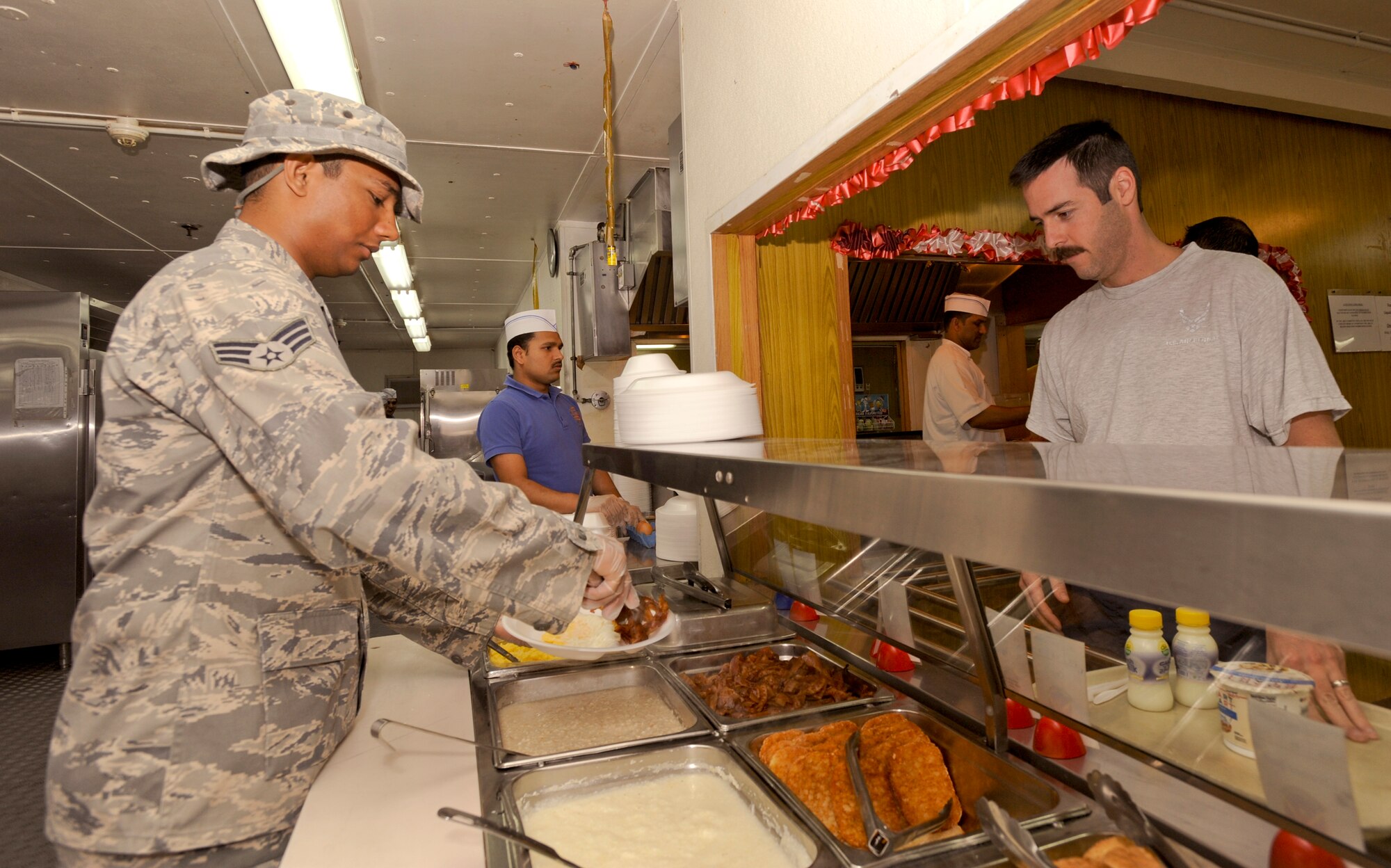 Senior Airman Cecil D'Souza, a services journeyman with the 379th Expeditionary Force Support Squadron, serves Major Corbit Bufton, a C-17 Globemaster III pilot with the 816th Expeditionary Airlift Squadron during the breakfast meal, March 23, 2009, in an undisclosed location in Southwest Asia. Military members working in the dining facilities aid local contract workers in serving and cooking the food during peak meal hours.  Airman D'Souza is native to Virginia and is deployed from McChord Air Force Base, Wash. in support of Operations Iraqi and Enduring Freedom and Combined Joint Task Force - Horn of Africa. (U.S. Air Force Photo by Staff Sgt. Joshua Garcia/released)