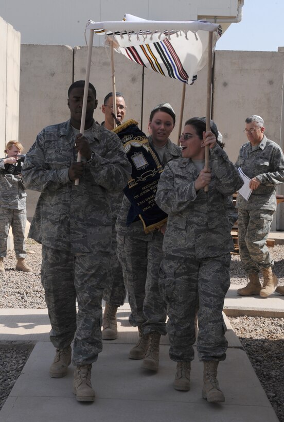 JOINT BASE BALAD, Iraq -- Members of the JBB community march in procession as Senior Airman Ann Leifer, 332nd Expeditionary Aerospace Medical Squadron aerospace medicine journeyman, carries JBB's first Torah into Gilbert Memorial Chapel during a dedication ceremony here March 21. The Torah, which was donated to JBB by the Jewish Welfare Board, contains the five books of Moses, Genesis, Exodus, Leviticus, Numbers and Deuteronomy, handwritten on a scroll of special parchment leather. It represents the foundation of Jewish law, teachings, religion and society. Leifer is deployed here from Westover Air Reserve Base, Mass. (U.S. Air Force photo/Senior Airman Elizabeth Rissmiller) 
