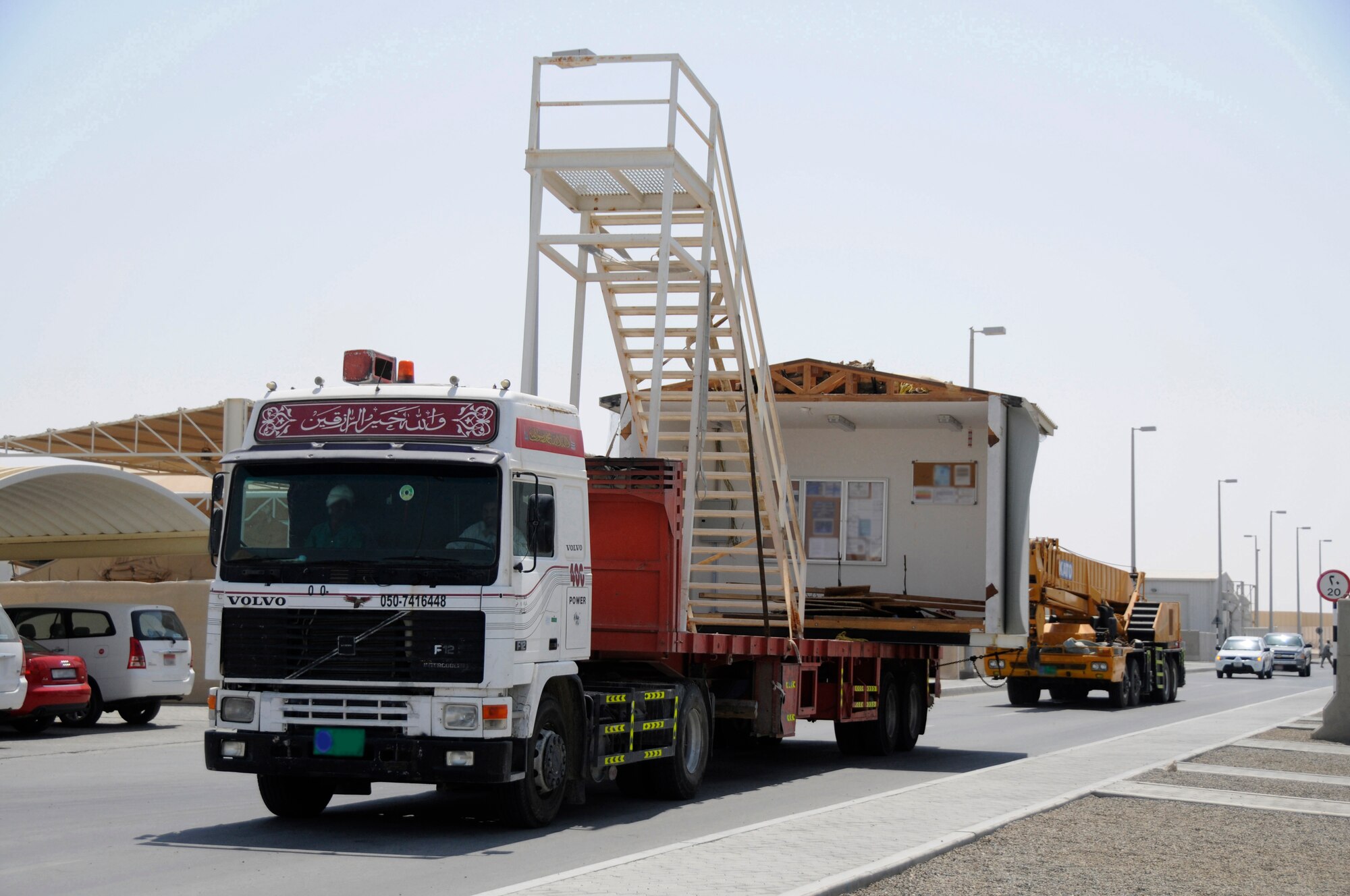 SOUTHWEST ASIA - A truck carrying a second story section of a building and a staircase is escorted to its new site, Mar 19. The building is used for lodging where new Airman and Soldiers can acquire room assignments and keys as well as pick-up linen for their beds. Lodging is also responsible for bedding down any distinguished visitors or diverted flight members to ensure their comfort. The lodging building was moved to make room for dormitory expansion. (U.S. Air Force photo by Senior Airman Brian J. Ellis) (Released)