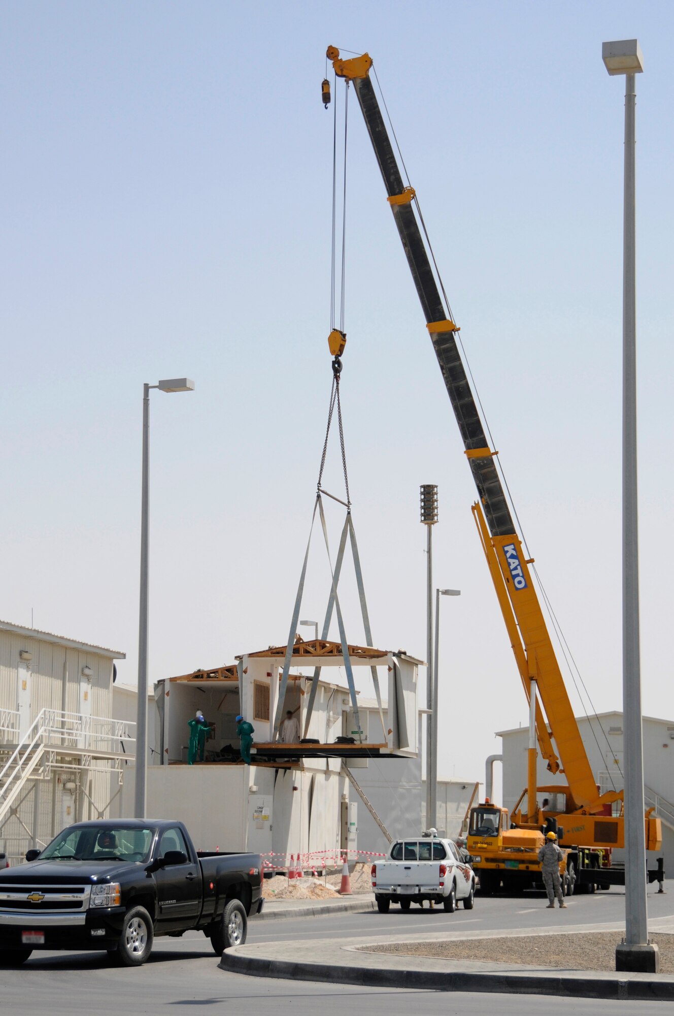 SOUTHWEST ASIA - A crane operated by a third country national lifts a section of the second story of a building onto its base, Mar 19. The building is used for lodging where new Airman and Soldiers can acquire room assignments and keys as well as pick-up linen for their beds. The lodging building was moved to make room for dormitory expansion. (U.S. Air Force photo by Senior Airman Brian J. Ellis) (Released)