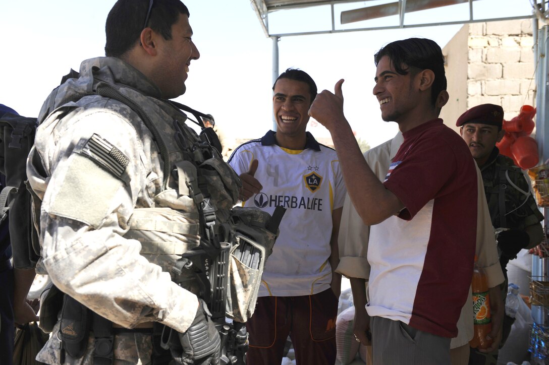 U.S. Army Sgt. 1st Class Roberto Roig spends time with local teens outside Al Mobid medical center in Az Zubayar district in Basra, Iraq, March 17, 2009.