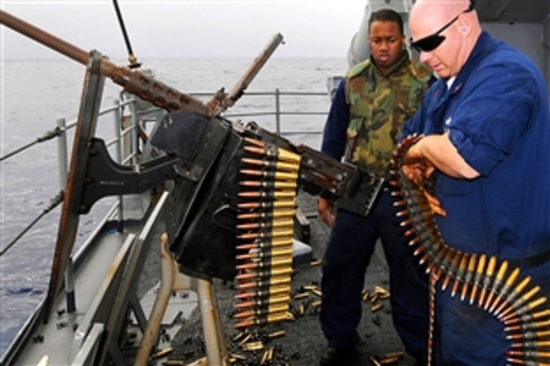 U.S. Navy Seaman LaJoel T. Rouse, left, waits his turn to qualify on a .50 caliber machine gun as U.S. Navy 1st Class Kevin B. Miller loads rounds into the weapon aboard the guided-missile cruiser USS Vella Gulf in the Atlantic Ocean, March 9, 2009.