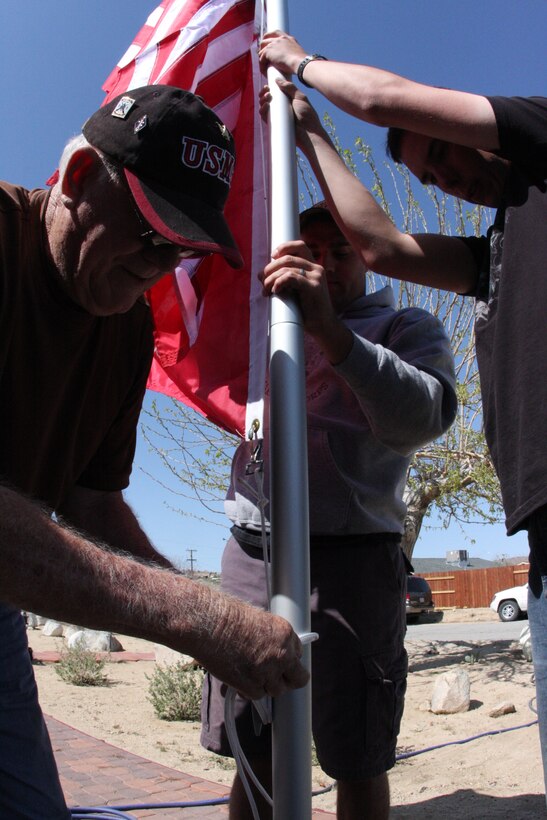 Korean War veteran Richard N. Blasongame fastens the rope on his brand-new flagpole that was built by Marines of 3rd Combat Engineers Battalion, outside his home in Joshua Tree, Calif., March 25.