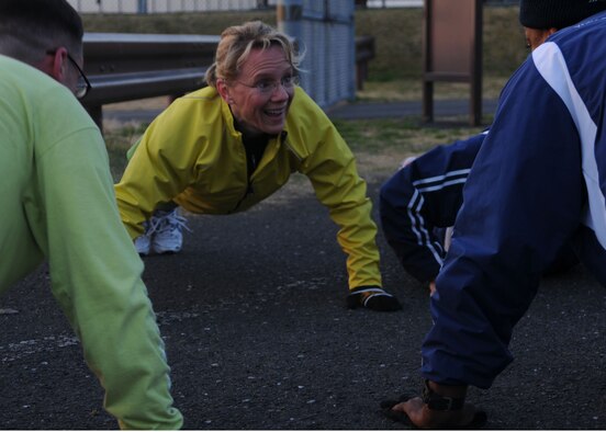 Maj. Peggy Cain, 374th Aerospace Medicine Squadron, Yokota Air Base, Japan, performs push-ups with fellow members of the Yokota Striders Running Club March 17 during an early-morning workout session. Club members train three days a week and once on the weekend to prepare for races throughout Japan. (U.S. Air Force photo/Airman Devin Doskey) 