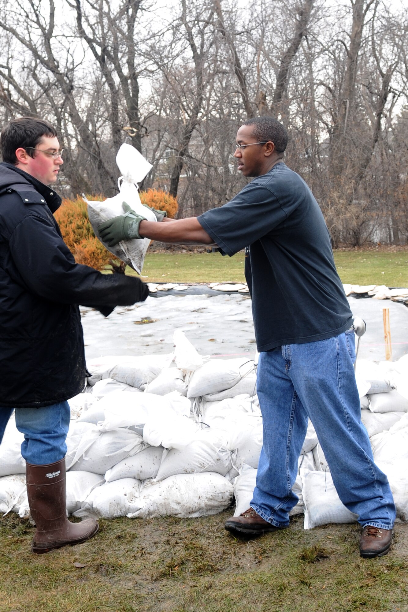 Staff Sgt. Nathaniel Newkirk, 319th Operations Support Squadron, hands off a sandbag to another volunteer while helping with flood preparations in a Fargo, N.D., neighborhood. Sergeant Newkirk is one of more than 100 Warriors of the North who have volunteered in the effort to mitigate flood damage in the Red River Valley to date. (U.S. Air Force photo/Tech. Sgt. Amanda Callahan)