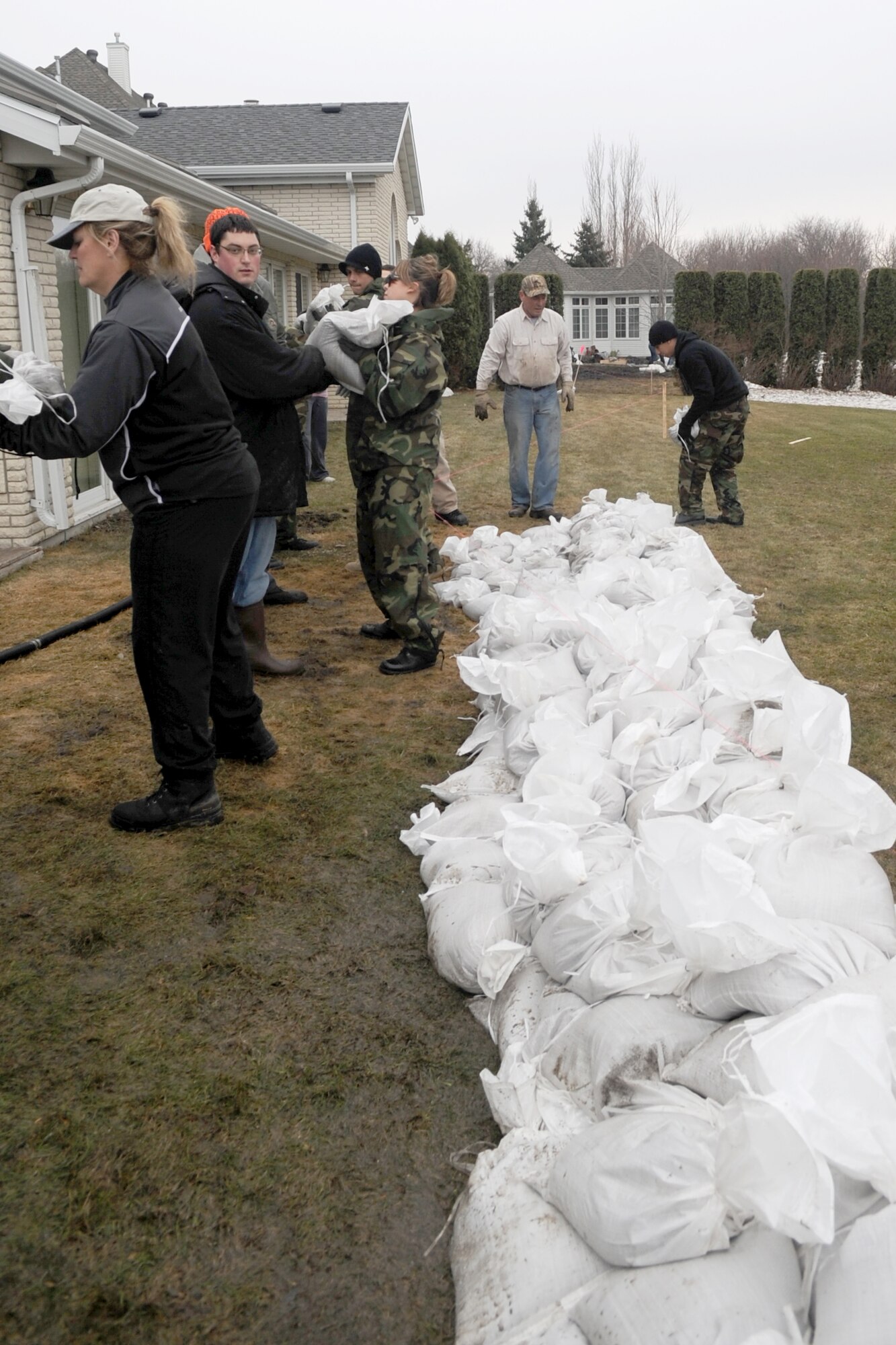 Volunteers and neighbors work together to protect homes from rising flood waters in a Fargo, N.D., neighborhood. Many Grand Forks Air Force Base teammates have volunteered throughout the region in support of flood protection efforts. (U.S. Air Force photo/Tech. Sgt. Amanda Callahan)
