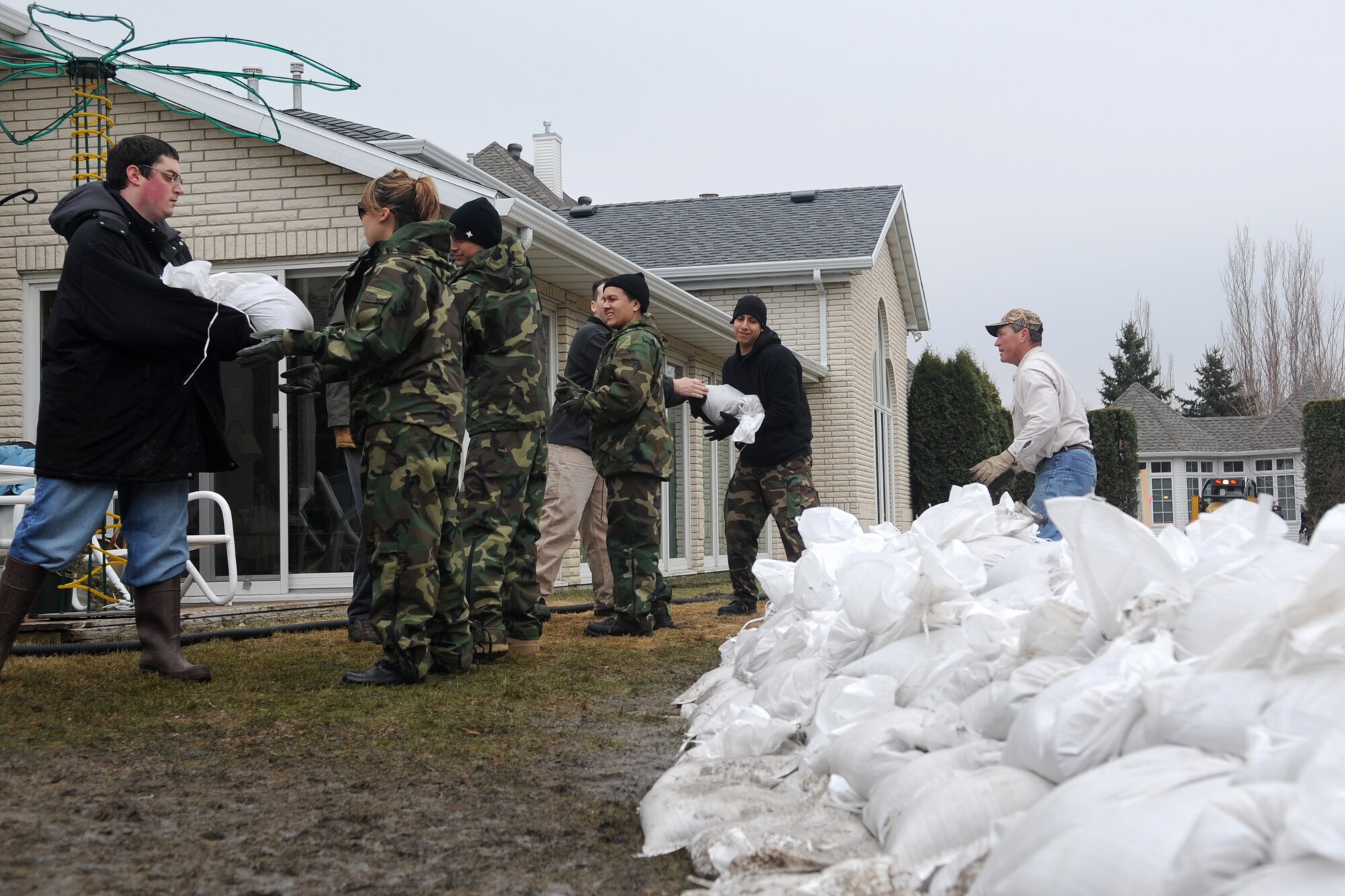 Volunteers and neighbors work together to protect homes from rising flood waters in a Fargo, N.D., neighborhood. Many Grand Forks Air Force Base teammates have volunteered throughout the region in support of flood protection efforts. (U.S. Air Force photo/Tech. Sgt. Amanda Callahan)