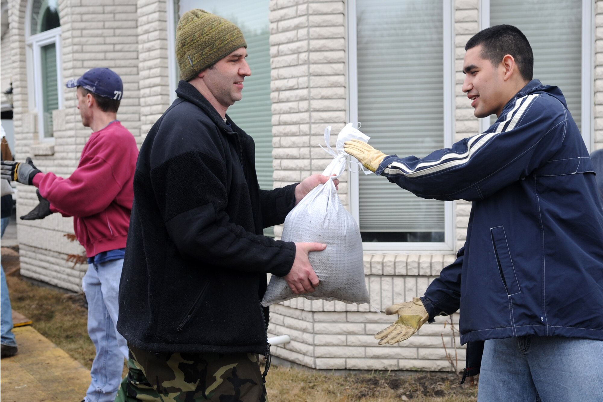 Tech. Sgt. Yancey Callahan (left) and Senior Airman Isaac Zavala, both of the 319th Operations Support Squadron, are part of a human sandbag chain comprised of neighbors and volunteers in Fargo, N.D. Warriors of the North are supporting the flood preparation efforts by volunteering at many locations throughout the Red River Valley. (U.S. Air Force photo/Tech. Sgt. Amanda Callahan)
