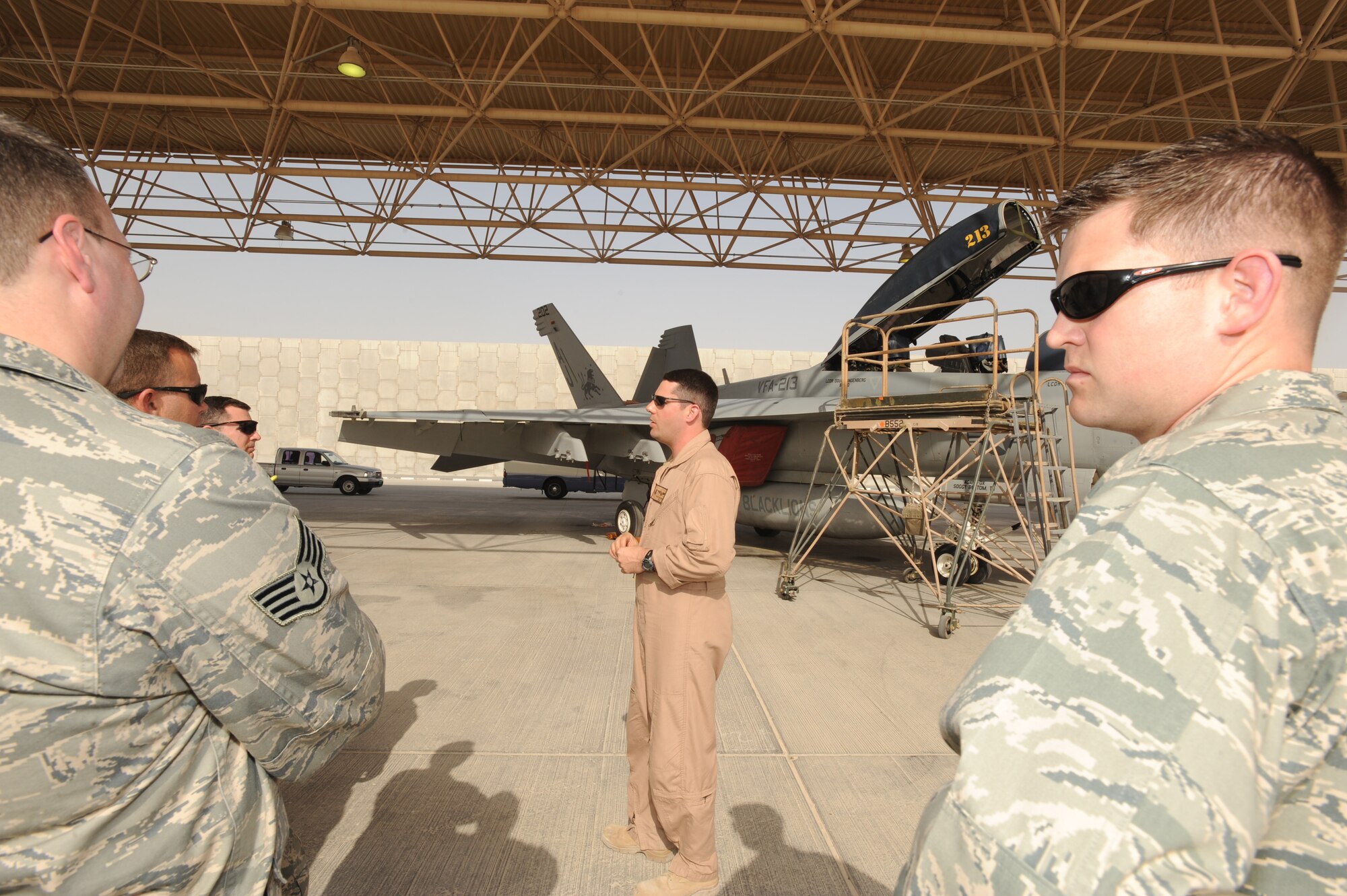 Lt. Cmdr. Doug Langenberg, a naval aviator from the U.S.S. Theodore Roosevelt's Strike Fighter Squadron 213, talks about the F/A-18F Super Hornet March 17 with Airmen from the 379th Air Expeditionary Wing at an air base in Southwest Asia who assisted the Sailors as they participated in Exercise Eastern Angler. The exercise is a regular event designed to foster good relations and provide a crossflow of ideas between U.S. and host nation servicemembers.  (U.S. Air Force photo/Staff Sgt. Joshua Garcia)