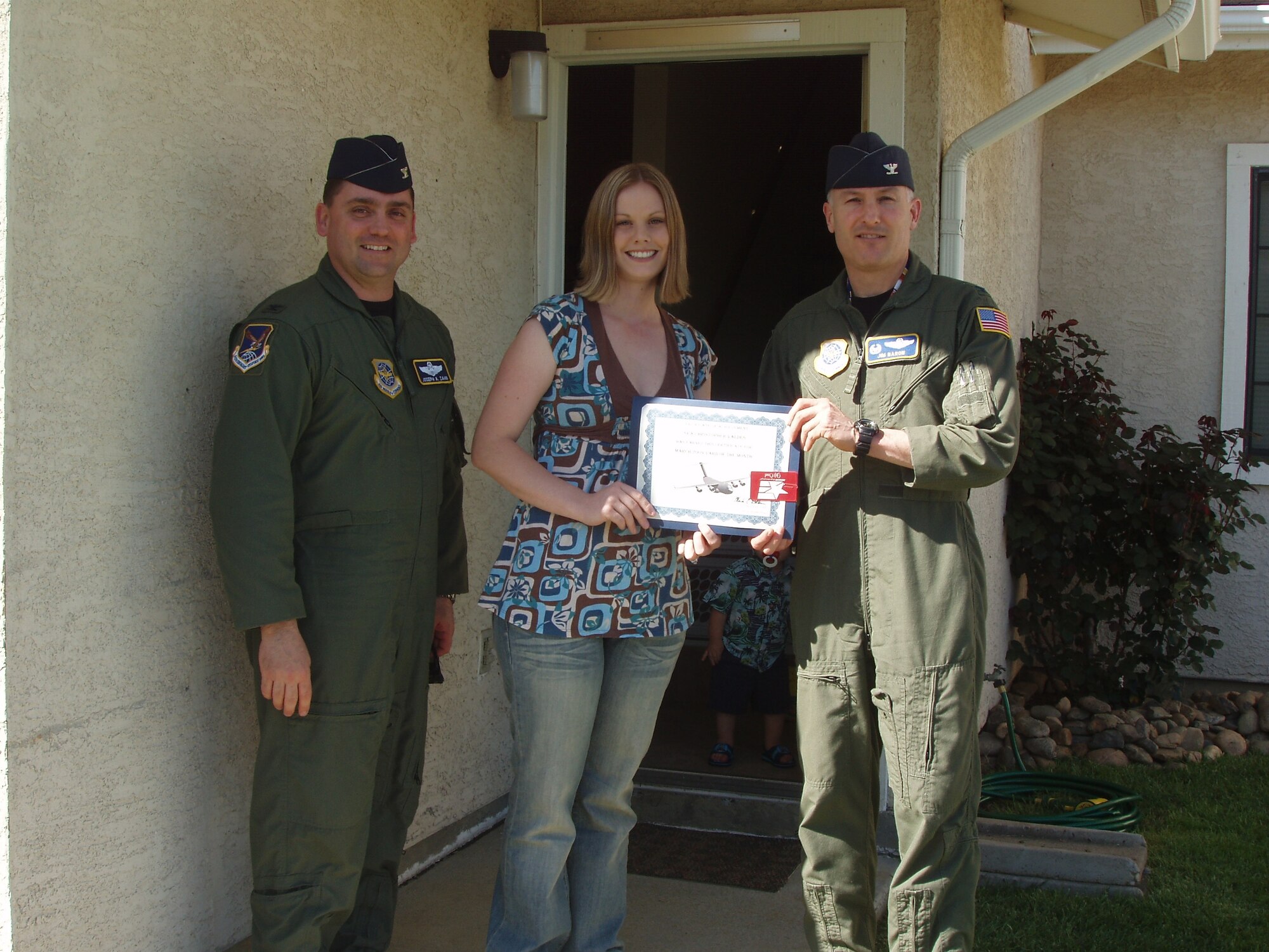 Col. Jim Baron, 60th Air Mobility Wing vice commander, and Col. Joseph Zahn, 615th Contingency Response Wing vice commander, present Amber Valdes the Yard of the Month award. Her husband, Staff Sgt. Christopher Valdes is deployed. The Valdes’ yard was recognized for pride in ownership, outstanding curb appeal and overall appearance. (U.S. Air Force photo/Master Sgt. Calvin Baumann)