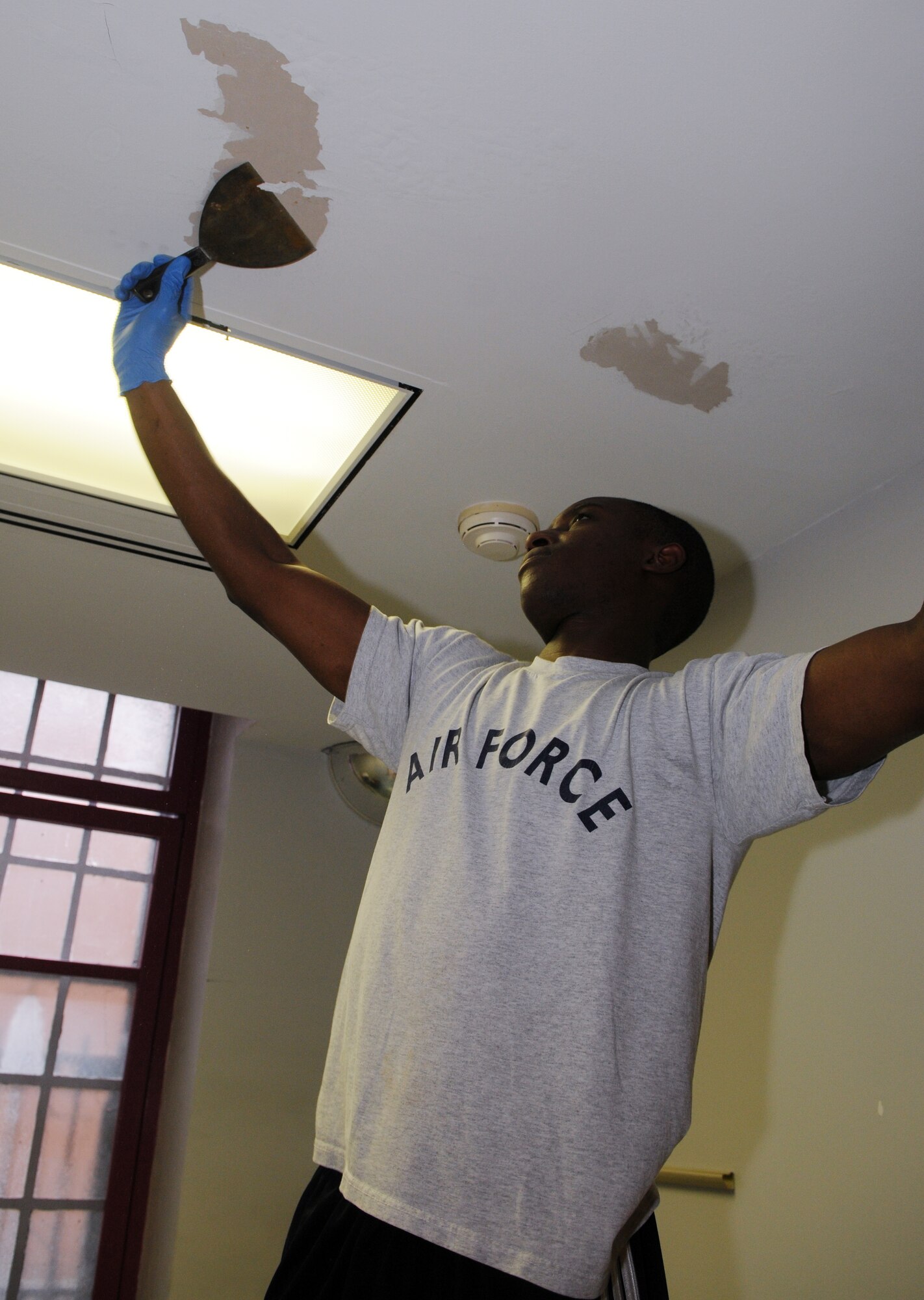 Staff Sgt. Kenneth Hawkins, 11th Contracting Squadron, scrapes paint from a ceiling in a treatment room during a painting project March 21 at Saint Elizabeth's Hospital, Washington. National Capital Region Airmen volunteered their weekend to help hospital staff members paint high-traffic areas used daily by patients and staff who are part of their treatment mall – the recovery program that patients attend Monday through Friday to prepare to return to the community. (U.S. Air Force Photo by Senior Airman Marleah Miller)