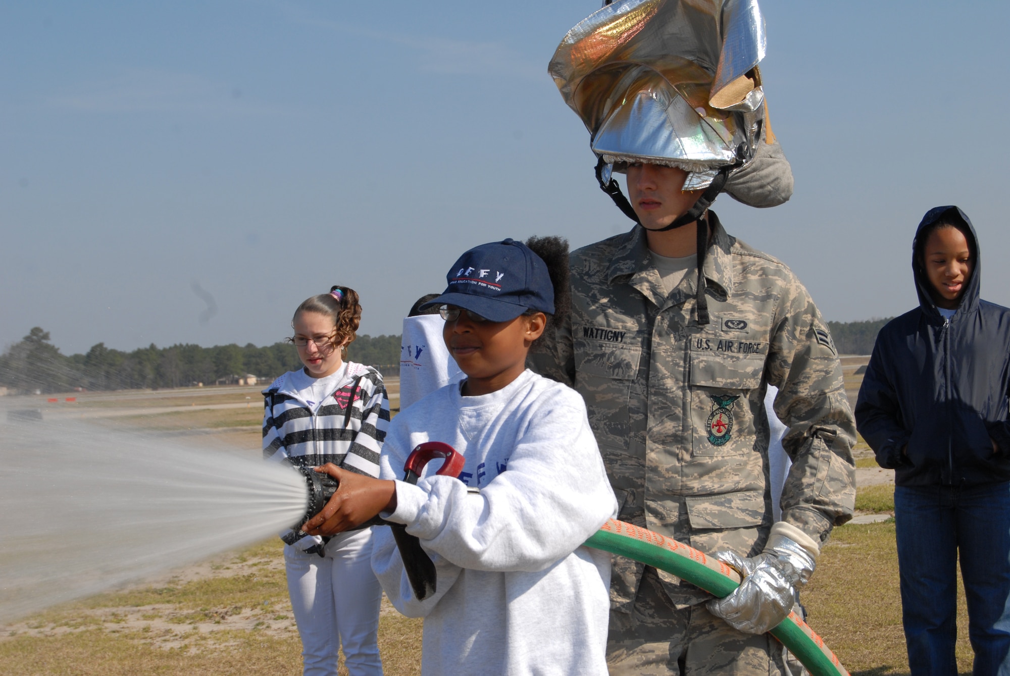 Airman 1st Class Joel Wattigny, 43rd Civil Engineer Squadron firefighter, shows Lauren Cunningham, 9, how to properly use a fire hose when the Drug Education For Youth campers visited the Pope fire station to learn about fire safety during a DEFY field trip March 21. (U.S. Air Force Photo by Airman 1st Class Mindy Bloem)
