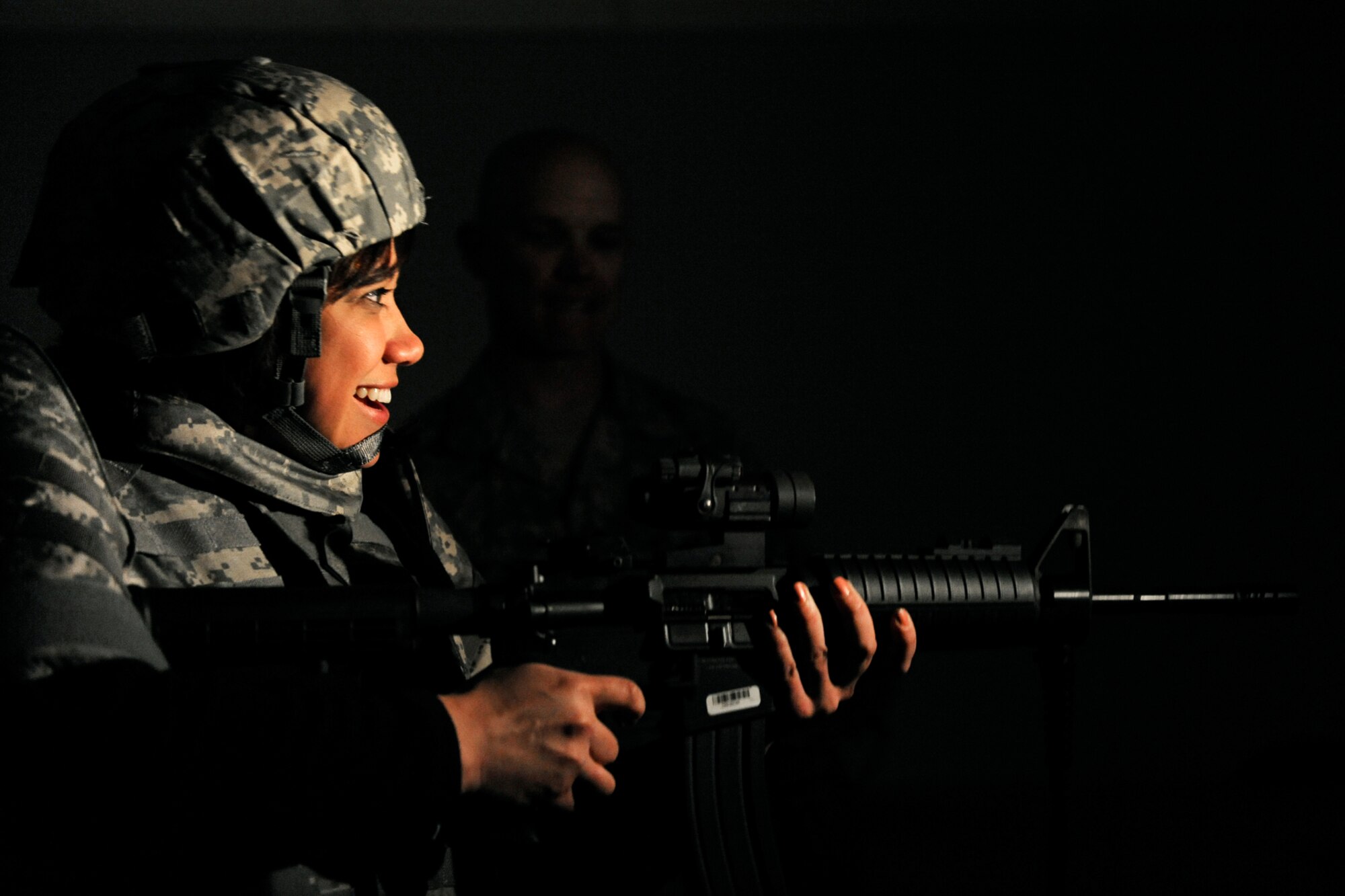 LANGLEY AIR FORCE BASE, Va. -- Mrs. Bianca Martinez, WTKR Channel 3 broadcaster, receives guidance from Master Sgt. Richard Thompson, 1st Security Forces Squadron combat arms non-commissioned officer in charge, as she practices firing an M-4 machine gun inside the combat arms simulator March 23.  Mrs. Martinez started a series entitled "Do My Military Job," which allows her to learn about various jobs within each branch of the military.  (U.S. Air Force photo/Senior Airman Vernon Young)