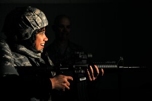 LANGLEY AIR FORCE BASE, Va. -- Mrs. Bianca Martinez, WTKR Channel 3 broadcaster, receives guidance from Master Sgt. Richard Thompson, 1st Security Forces Squadron combat arms non-commissioned officer in charge, as she practices firing an M-4 machine gun inside the combat arms simulator March 23.  Mrs. Martinez started a series entitled "Do My Military Job," which allows her to learn about various jobs within each branch of the military.  (U.S. Air Force photo/Senior Airman Vernon Young)