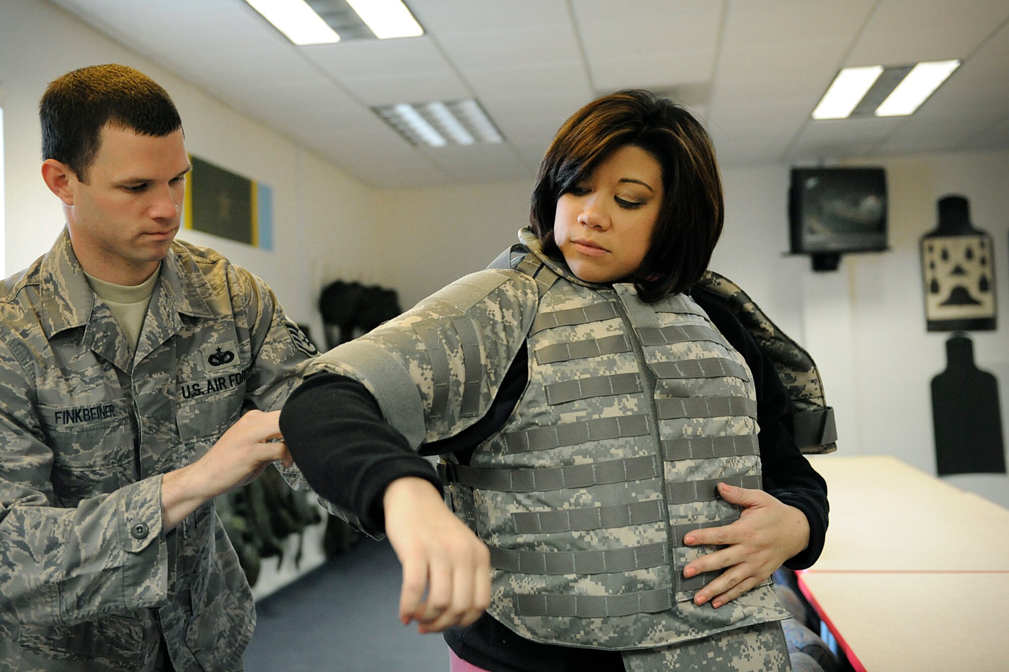 LANGLEY AIR FORCE BASE, Va. -- Staff Sgt. Joshua Finkbeiner, 1st Security Forces Squadron readiness technician, prepares Mrs. Bianca Martinez, WTKR Channel 3 broadcaster, with protective gear before entering the combat arms simulator, here March 23.  Mrs. Martinez started a series entitled "Do My Military Job", which allows her to learn about various jobs within each branch of the military.   (U.S. Air Force photo/Senior Airman Vernon Young)