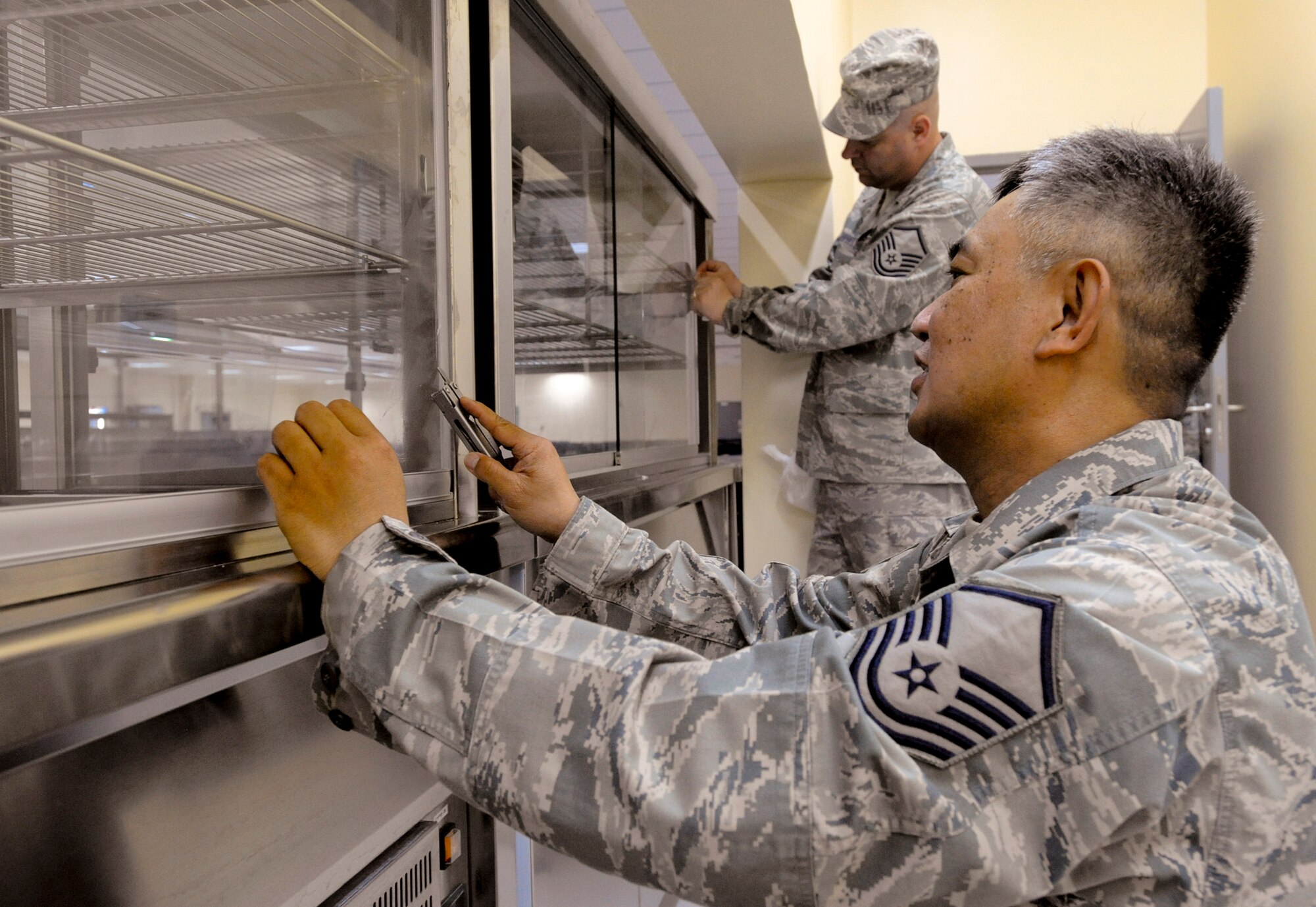 Master Sgt. Ramon Erpelo and Master Sgt. Robert Campbell sanitize and set up equipment in the new Coalition Compound Dining Facility March 23 at an air base in Southwest Asia. The new dining facility, scheduled to open soon, will have a state of the art kitchen to feed the servicemembers stationed here. Sergeant Eperlo is native to Chicago and is deployed from McChord Air Force Base, Wash. Sergeant Campbell is from Anchorage, Alaska, and deployed from Elmendorf AFB, Alaska. Both are assigned to the 379th Expeditionary Force Support Squadron. (U.S. Air Force photo/Staff Sgt. Joshua Garcia) 
