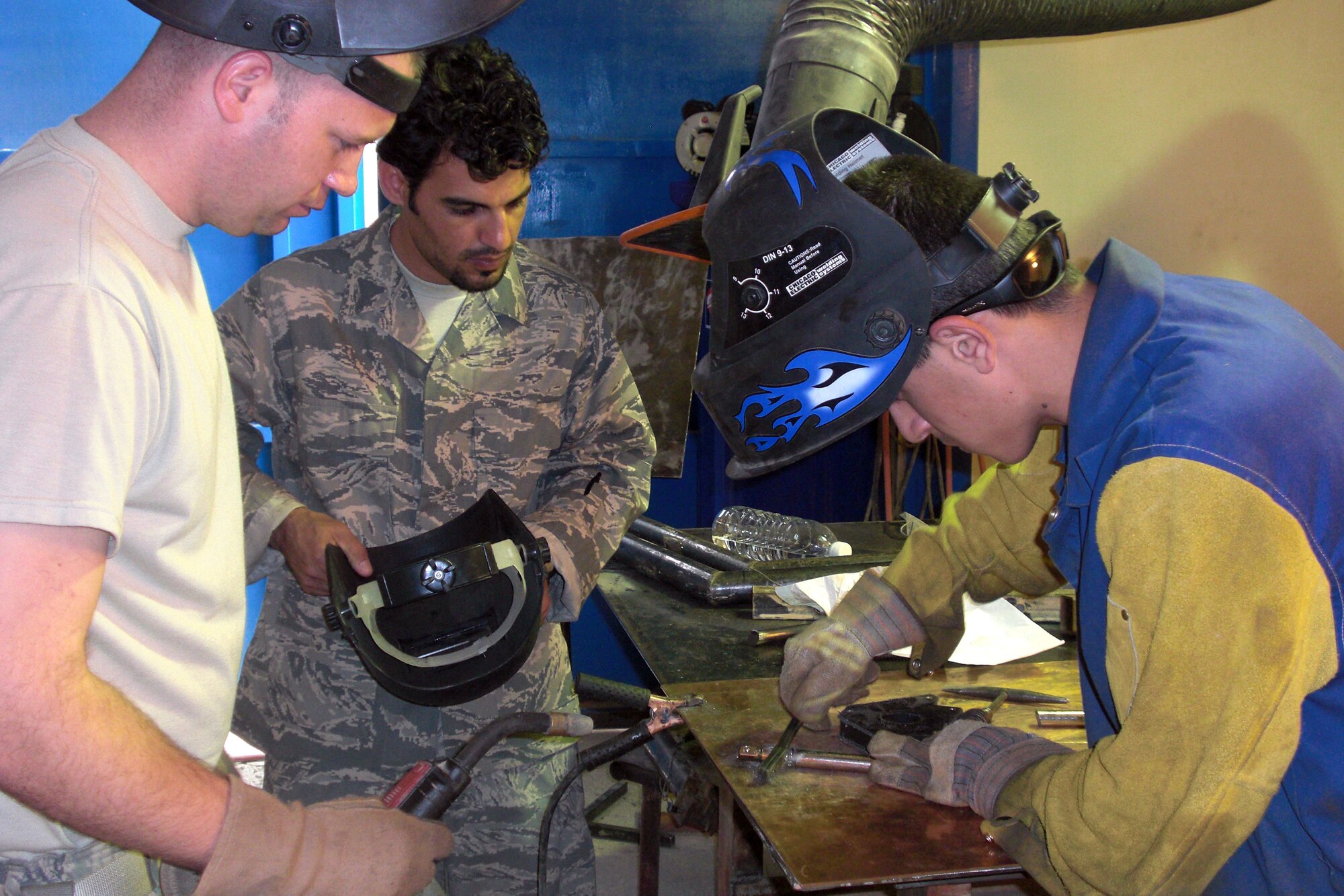 Technical Sgt. Bobby McKenzie (left) and an Iraqi interpreter look on while an Iraqi machinist fabricates a torque tool for C-130 main landing gear brakes March 24 at Camp Taji, Iraq. Sergeant McKenzie took three Iraqi air force members to Camp Taji to help better cross utilize their resources and also fix an Iraqi C-130s. Sergeant McKenzie is a 321st Air Expeditionary Advisory Squadron aircraft structural maintenance adviser. He is deployed from Little Rock Air Force Base, Ark., and is a native of Manchester, Tenn. (Courtesy photo) 
