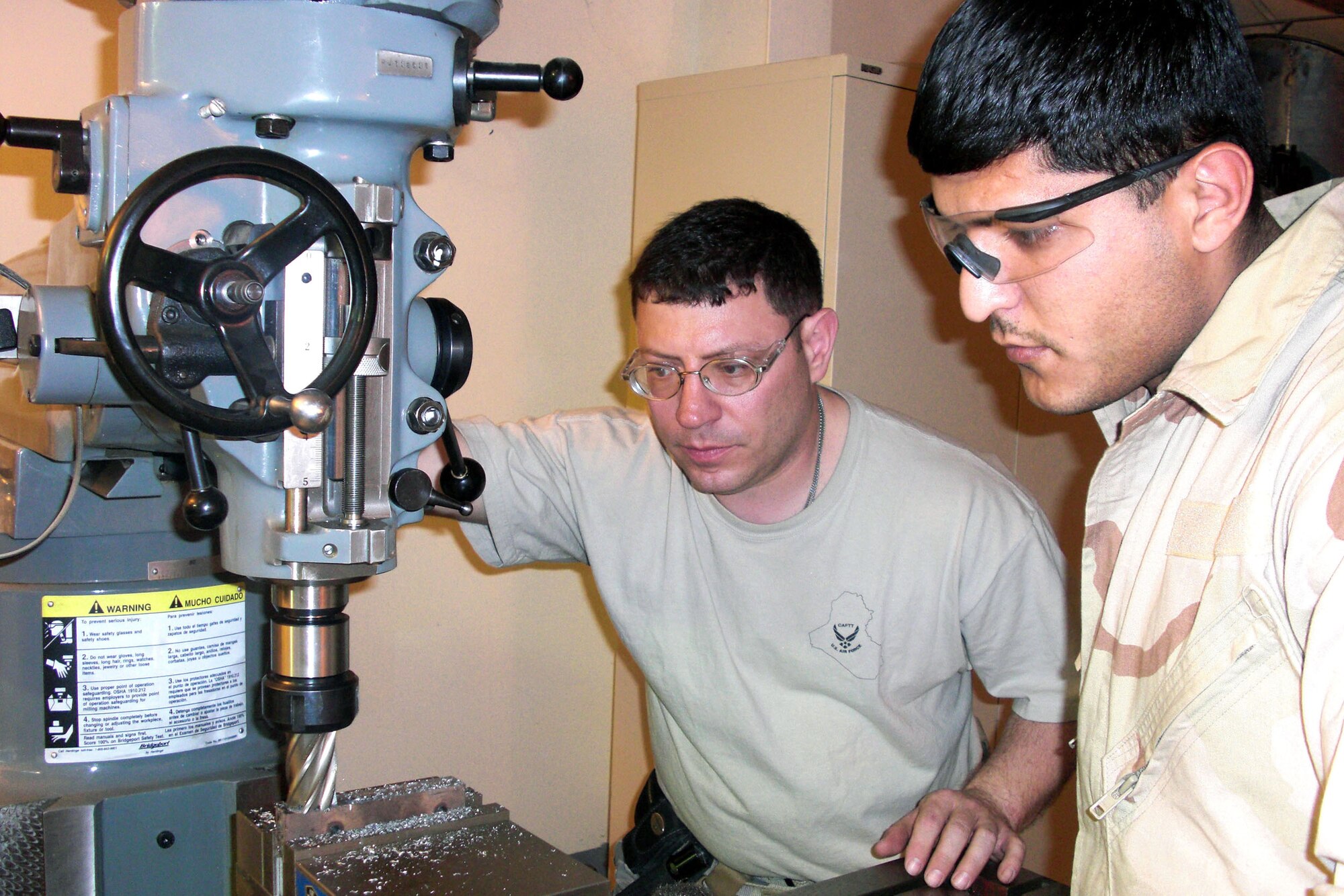At Camp Taji, Iraq, Tech. Sgt. Jim Grifasi observes and instructs Iraqi machinist Ehab while he operates a milling machine to perform a C-130 Hercules wing inspection March 24. Sergeant Grisasi is a 321st Air Expeditionary Advisory Squadron metals technician adviser. (Courtesy photo)
