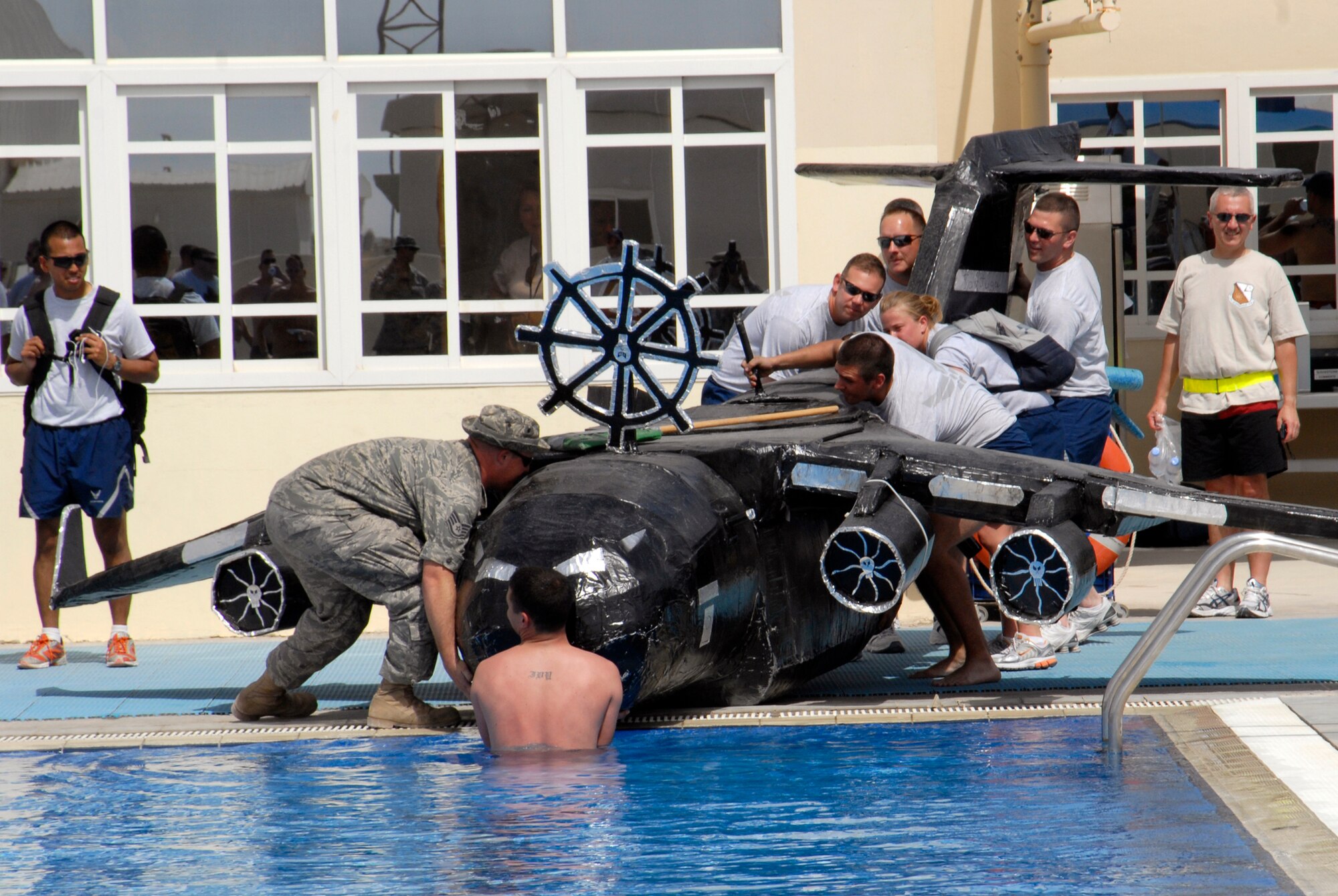Personnel from all different military services participate in a build-your-own cardboard boat race in the Coalition Compound pool, Mar. 22, 2009, at an undisclosed location in Southwest Asia.  Services hosted the event for the 379th Expeditionary Force Support Squadron to provide a welcomed relief for servicemembers deployed in support of Operations Iraqi and Enduring Freedom and Combined Joint Task Force - Horn of Africa.  (U.S. Air Force photo/Senior Airman Andrew Satran/released)