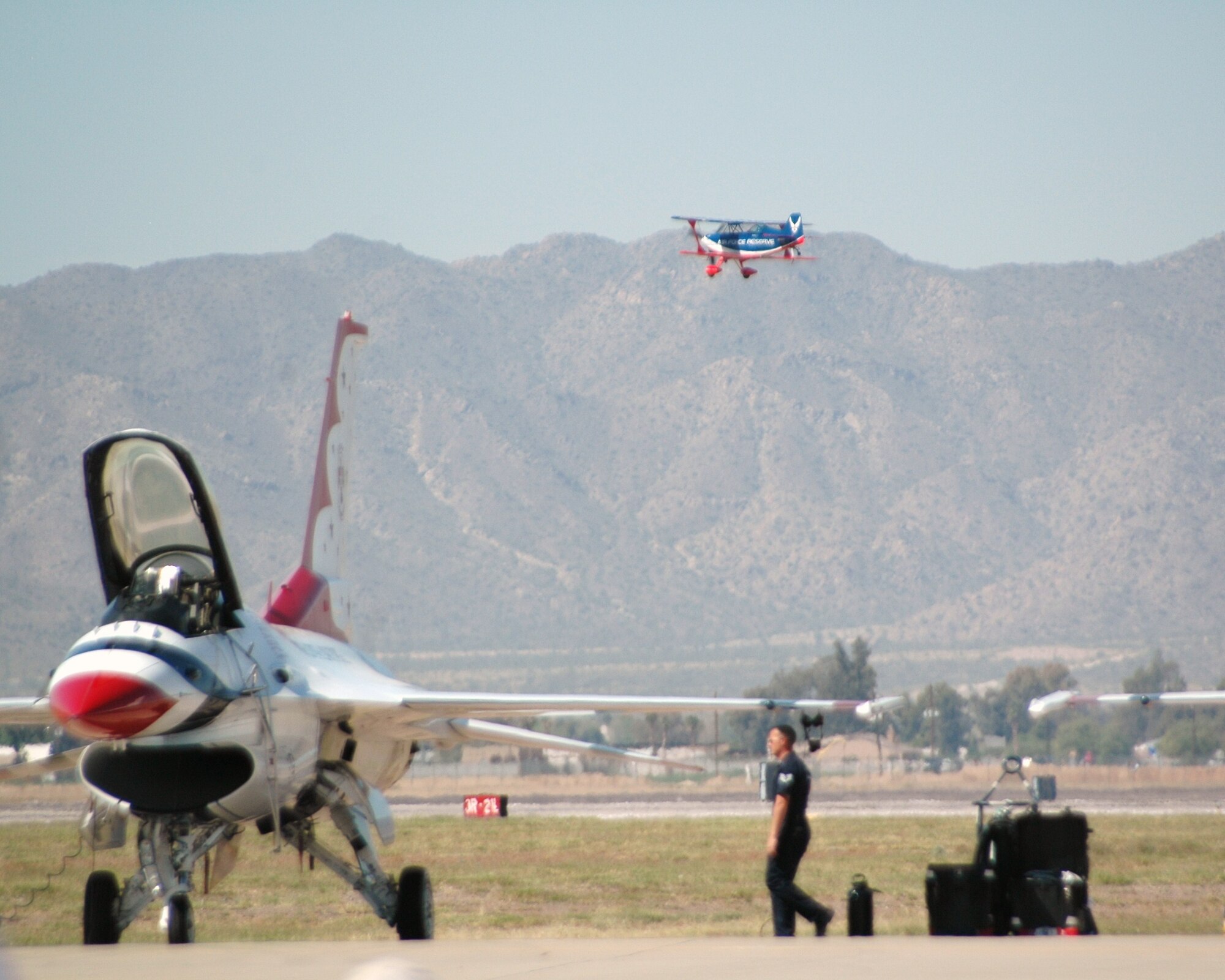 Ed Hamill, in the Air Force Reserve biplane, flies over one of the U.S. Air Force Thunderbirds at Luke Air Force Base, Ariz., March 21. Both the Thunderbirds and Mr. Hamill performed at "Thunder in the Desert," Luke's two-day open house and air show March 21 and 22. As the U.S. Air Force Air Demonstration Squadron, the Thunderbirds perform precision aerial maneuvers demonstrating the capabilities of Air Force high performance aircraft to people throughout the world. Mr. Hamill is an Air Force Reserve lieutenant colonel who serves as an instructor pilot with the 944th Fighter Wing at Luke AFB. He performs at air shows around the country, highlighting the history of air show flying while promoting the Air Force Reserve. (U.S. Air Force photo/Tech. Sgt. Susan Stout) 
