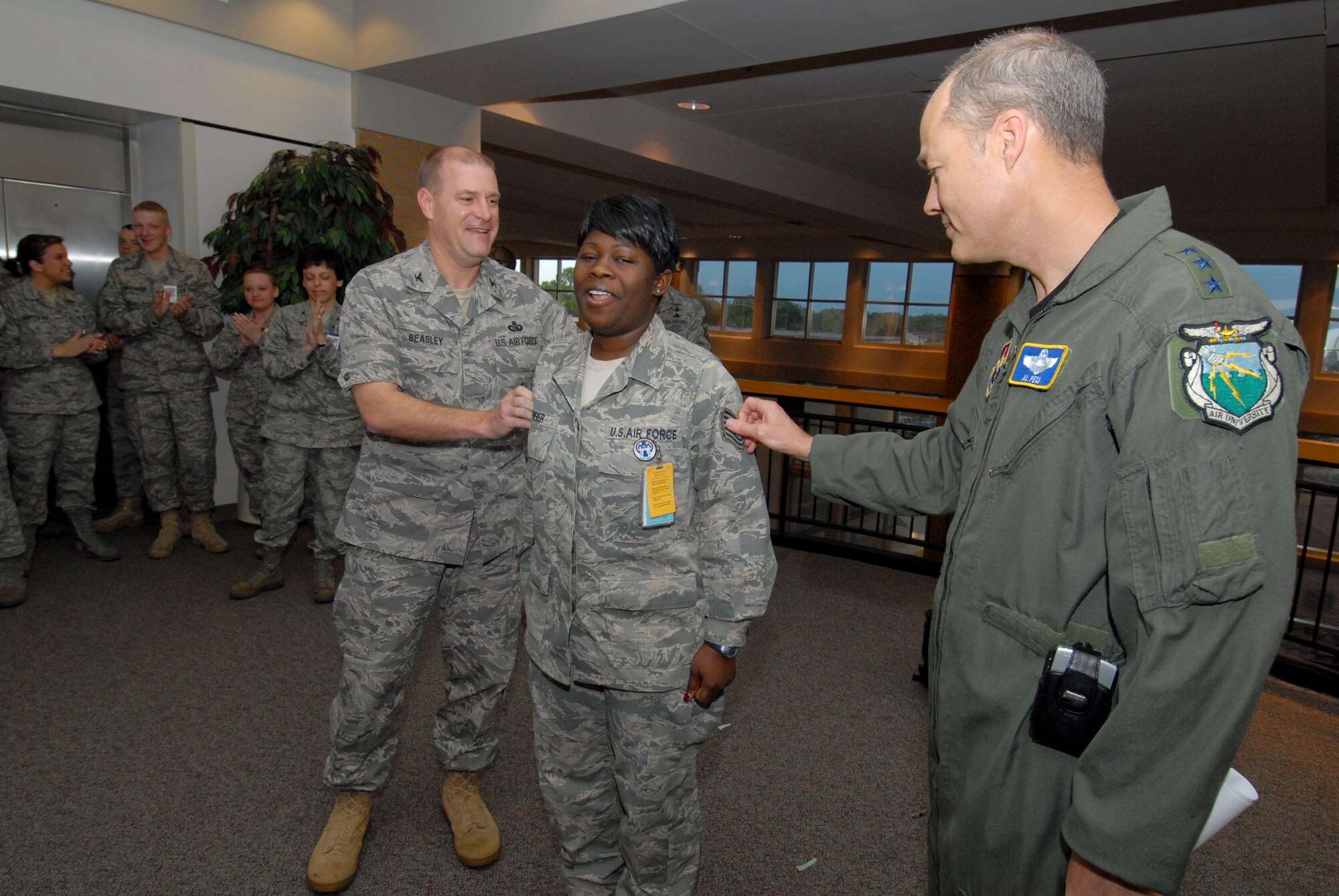 Lt. Gen. Allen Peck (right), Air University commander, and Col. Kris Beasley (left), 42nd Air Base Wing commander, attach new stripes to Tech. Sgt. Shawone Riser, non-commissioned officer in charge of medical information systems at the 42nd Medical Group. Sergeant Riser was selected for a STEP promotion to technical sergeant by General Stephen Lorenz, commander of Air Education and Training Command. (Air Force photo by Jamie Pitcher)