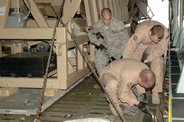 Tech. Sgt. Charles Moore, front, Airman 1st Class Chris Regalia, center, and Airman 1st Class David Marcum, back, secure a Mine-Resistant, Ambush-Protected egress simulator onto a C-5 here March 20. The simulators are used to train deployed military members how to egress out of a MRAP that has overturned. Sergeant Moore and Airman Regalia are with the 167th Airlift Wing, Air National Guard, W. Va. Airman Marcum is with the 437th Aerial Port Squadron. (U.S. Air Force photo/Staff Sgt. Marie Cassetty)(RELEASED)