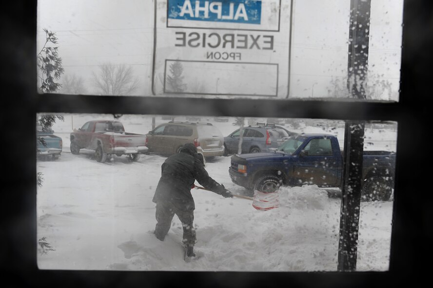MINOT AIR FORCE BASE, N.D. – Senior Airman Joe Rivera, a photographer from Minot AFB public affairs, shovels the side entrance to the 5th Bomb Wing Headquarters building during a blizzard hereMarch 24. Airmen from the 5th Bomb Wing and 91st Missile Wing were released early due to the forecasted hazardous weather conditions. (U.S. Air Force photo by Senior Airman Kelly Timney)