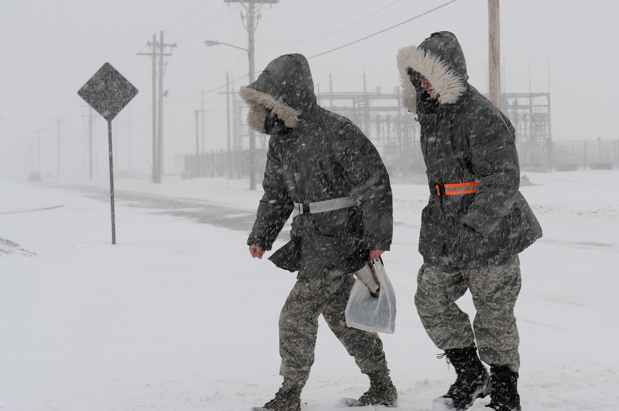 MINOT AIR FORCE BASE, N.D. – Senior Airman Osha Parker, a refueling equipment operator, and Senior Airman Louis Solsbury, a fuels distribution journeyman, both from the 5th Logistics Readiness Squadron, cross Bomber Boulevard as they head to work during a blizzard here March 24.  Airmen from the 5th Bomb Wing and 91st Missile Wing were released early due to the forecasted hazardous weather conditions. 2009 was a year that brought progress and a renewed emphasis on safe, secure and reliable nuclear operations. The 91st Missile Wing transitioned to Air Force Global Strike Command with the 5th Bomb Wing scheduled to follow suit in 2010. (U.S. Air Force photo by Senior Airman Kelly Timney)