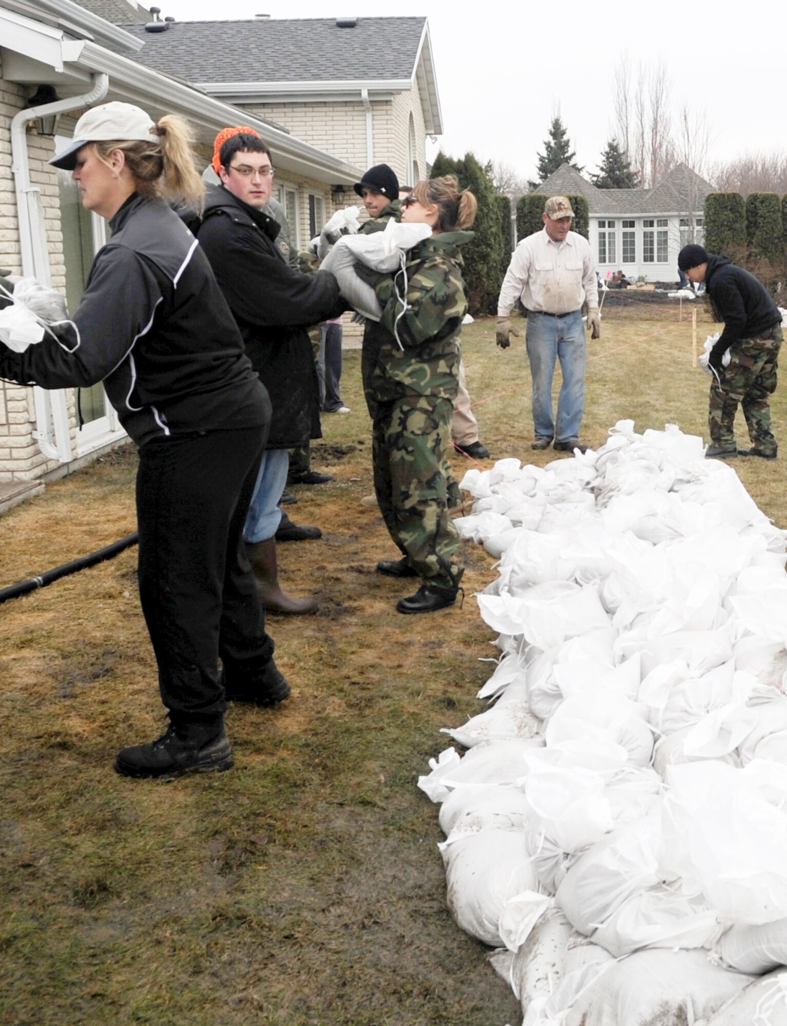 Volunteers and neighbors work together to protect homes from rising flood waters in a Fargo, N.D., neighborhood. Many Grand Forks Air Force Base, N.D.,  Airmen have volunteered throughout the region to support flood protection efforts. (U.S. Air Force photo/Tech. Sgt. Amanda Callahan)