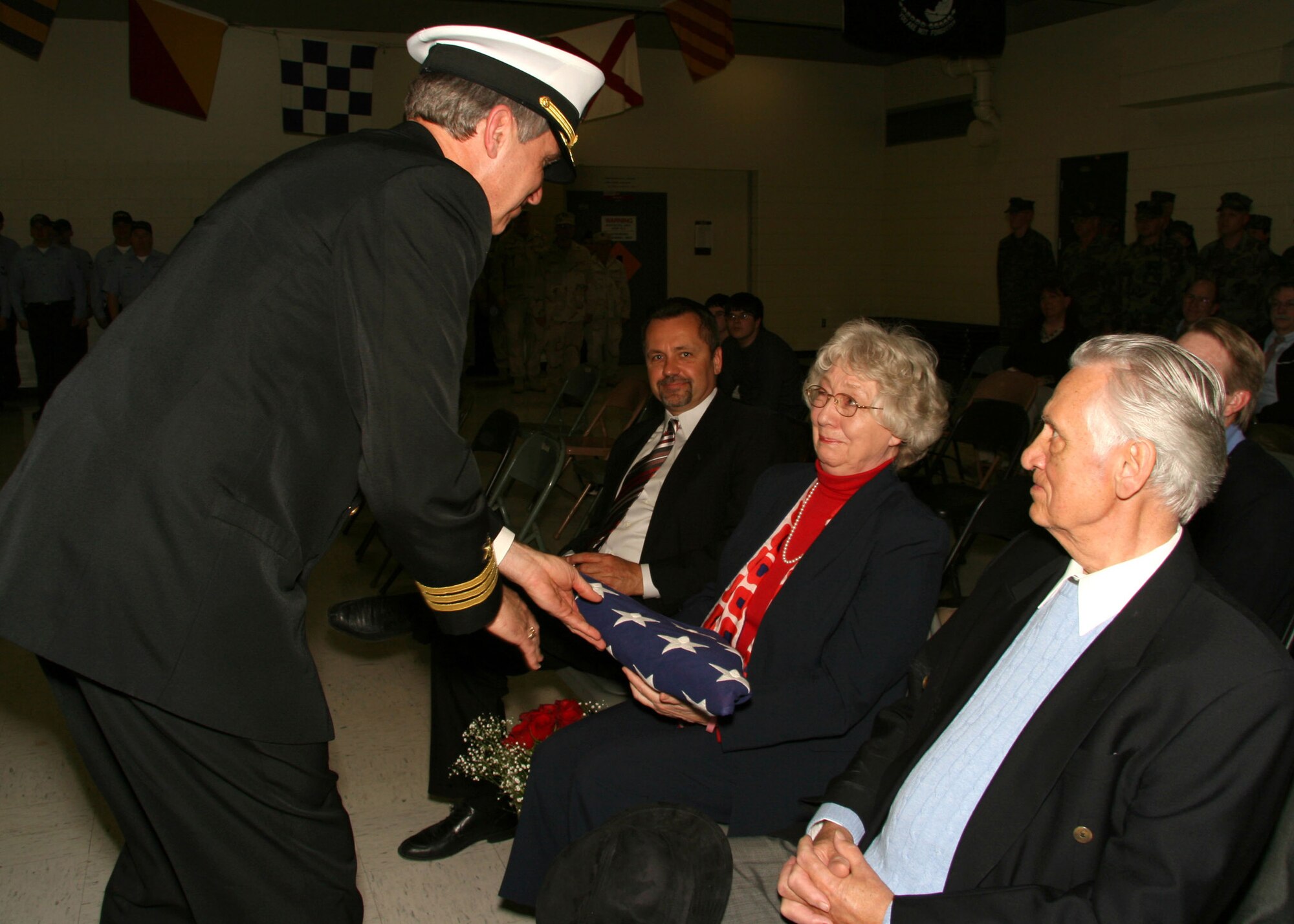 WICHITA, Kan. -- U.S. Navy Cmdr. Michael Boettcher presents his mother Lucie Boettcher and her husband John, with the national ensign during his retirement ceremony, March 14, held at the Naval Operational Support Center in Wichita. The retired naval aviator currently resides in Wichita and is employed as a flight safety instructor at Mid-Continent Airport. (U.S. Navy photo by Mass Communication Specialist 2nd Class Ron Trevino)