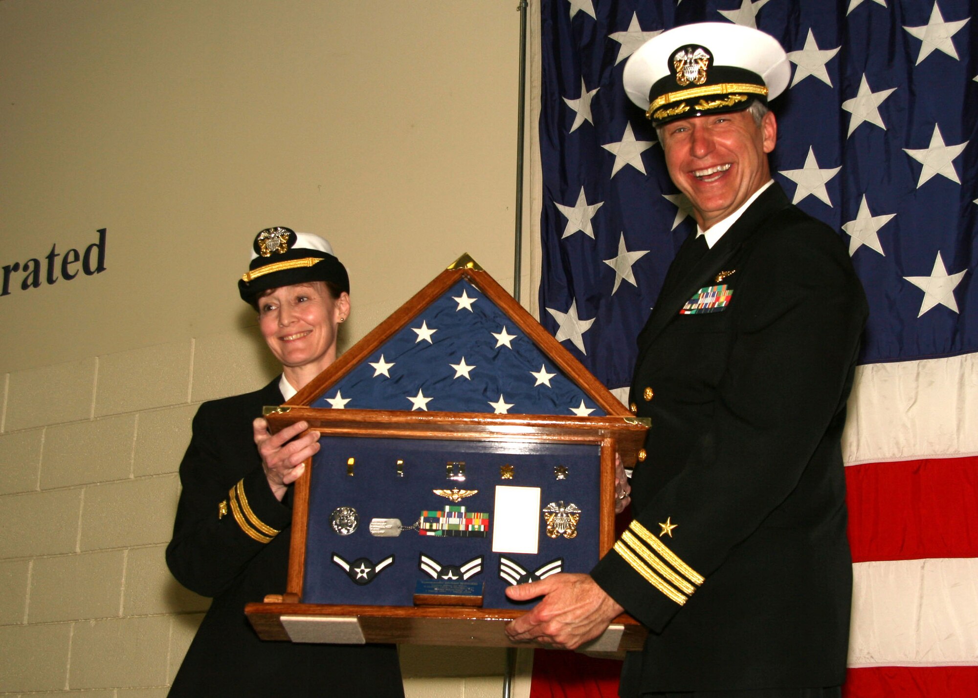 WICHITA, Kan. -- Navy Lt.  Linda Ashford presents Cmdr. Michael Boettcher with a shadow box during his retirement, March 14, after 34 years of distinguished military service. The ceremony was held at Naval Operational Support Center in Wichita. Commander Boettcher held the position of commanding officer of the volunteer training unit. (U.S. Navy photo by Mass Communication Specialist 2nd Class Ron Trevino)