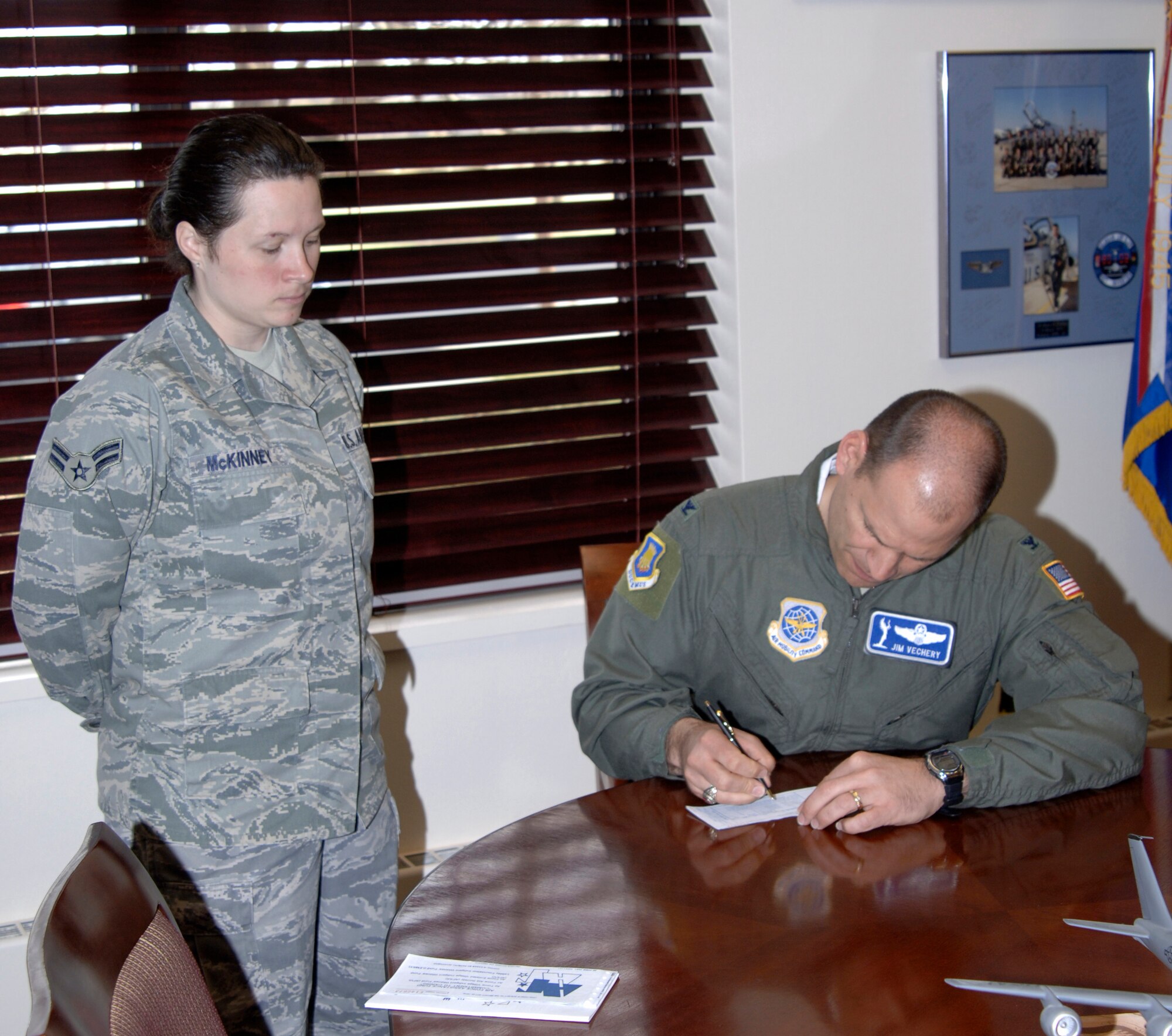 MCCONNELL AIR FORCE BASE, Kan. -- Airman 1st Class Tonya McKinney, 22nd Comptroller Squadron, watches as Col. James C. Vechery, 22nd Air Refueling Wing commander, fills out a form for the Air Force Assistance Fund in his office, March 18. The Air Force Assistance Fund supports four official Air Force charities; the Air Force Village Foundation, Inc.; the Air Force Aid Society, Inc.; the General and Mrs. Curtis E. LeMay Foundation; and the Air Force Enlisted Village, Inc. (Photo by Senior Airman Laura Suttles)