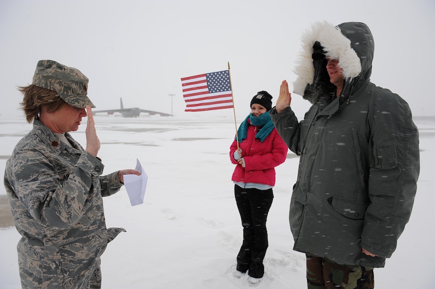 MINOT AIR FORCE BASE, N.D. – Senior Airman Wesley Wright, Minot AFB public affairs staff writer, stands on the flightline and recites the oath of enlistment read by Maj. Laurie Arellano, Chief of Minot AFB Public Affairs, during a blizzard here March 24. Airman Wright wanted to create a memorable first re-enlistment by standing in front of a B-52H Stratofortress in Minot AFB’s infamous winter weather before he and his wife Jessica move to their next base in Lakenheath, England this fall. (U.S. Air Force photo by Senior Airman Kelly Timney)
