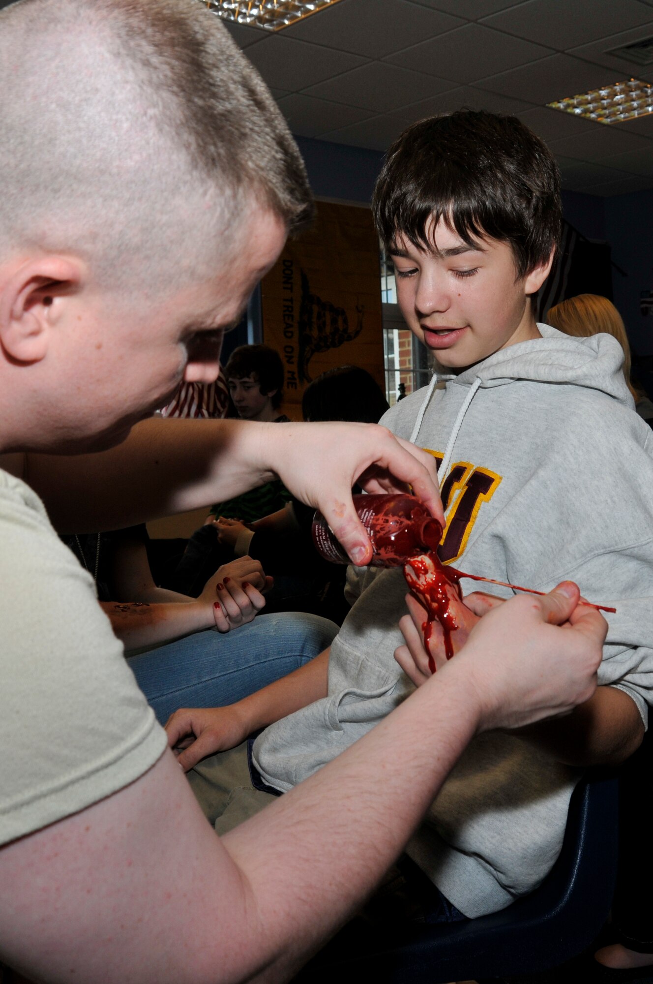 Tech Sgt. Victor Malone, 48th Medical Group NCO in charge of clinical education pours fake blood on Derrick Hoopes, son of Capt. Jerry Hoopes, 48th Medical Operations Squadron as part of a simulated amputation March 23, 2009 at RAF Feltwell, England. Moulage is the art of applying mock injuries for the purpose of training first responders and emergency medical personnel (U.S. Air Force photo by Airman 1st Class Perry Aston)
