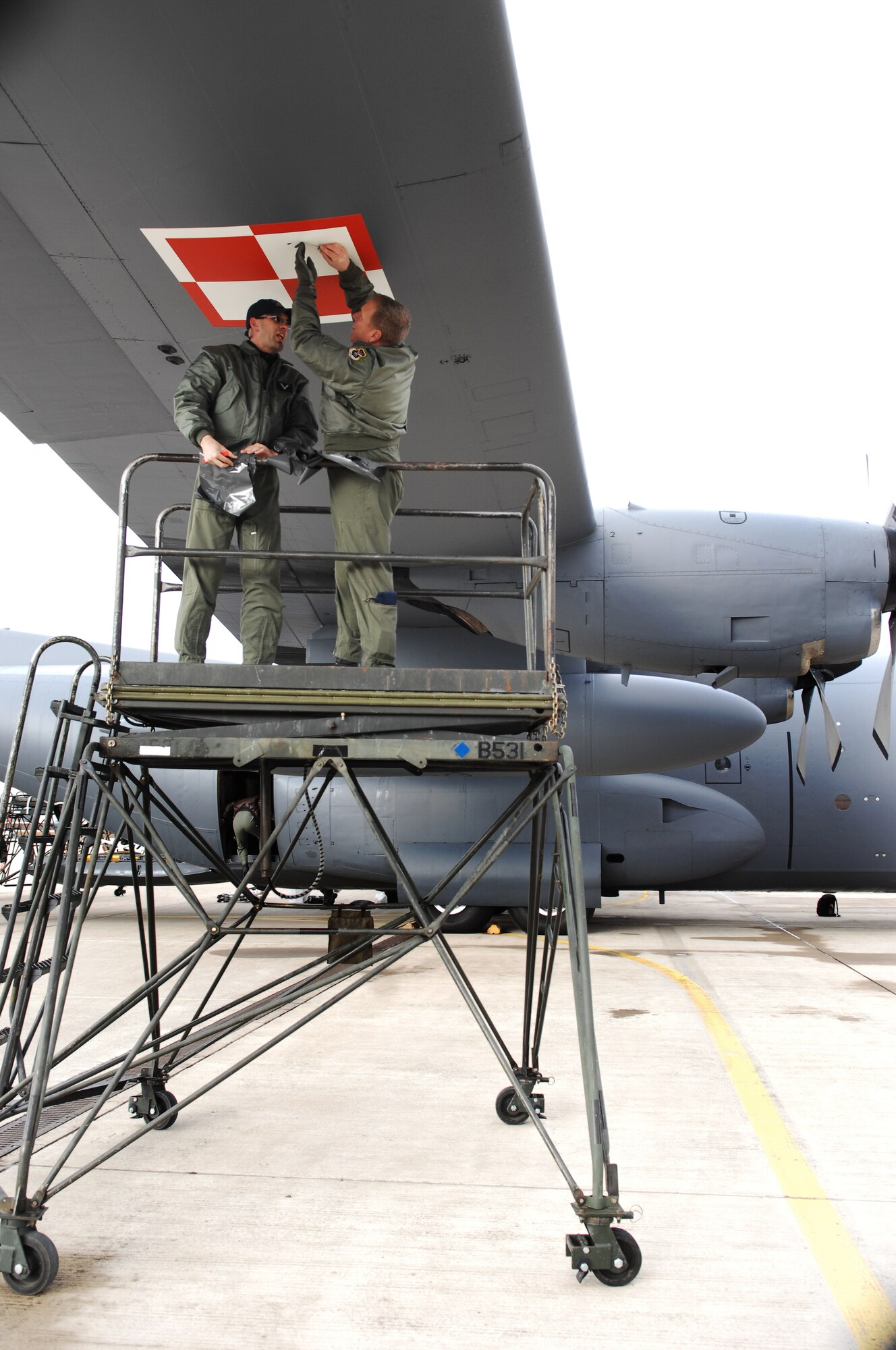 Polish Air Force Sergeant (E-5) Andy Kozera (left), 14th Lift Squadron, Powidz Air Base, and U.S. Air Force Master Sgt. Ron Whitehead, 514th Flight Test Squadron, Hill Air Force Base, UT, change the decals on a C-130E Hercules aircraft to the Polish Air Force sign, Mar. 23, 2009, Ramstein Air Base, Germany. Today the Polish Air Force receives the first C-130 Hercules aircraft from the U.S. Air Force.  (U.S. Air Force photo by Senior Airman Amber Bressler)(Released)